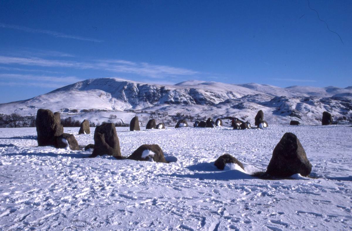 The Castlerigg stones standing in deep snow with the snow-covered fells behind