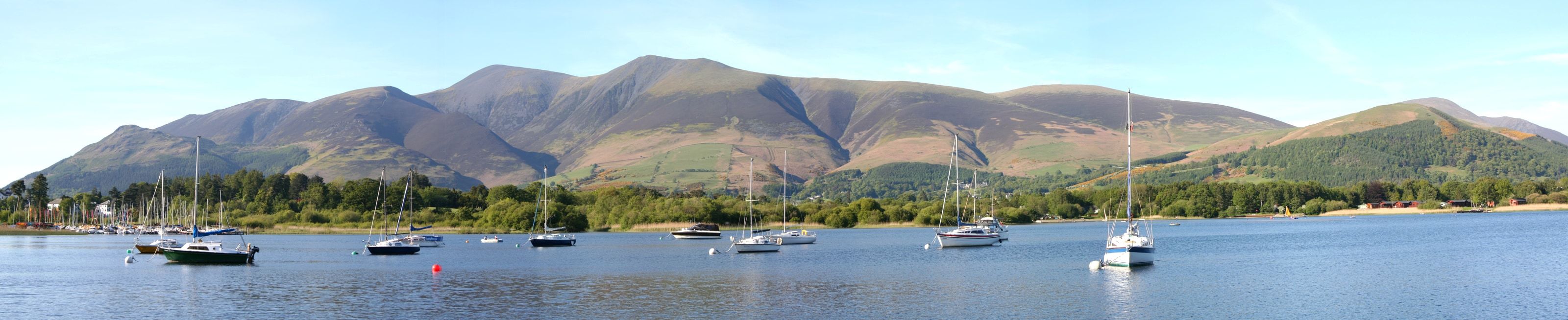 Yachts at their moorings on Bassenthwaite Lake with the long fell ridge behind