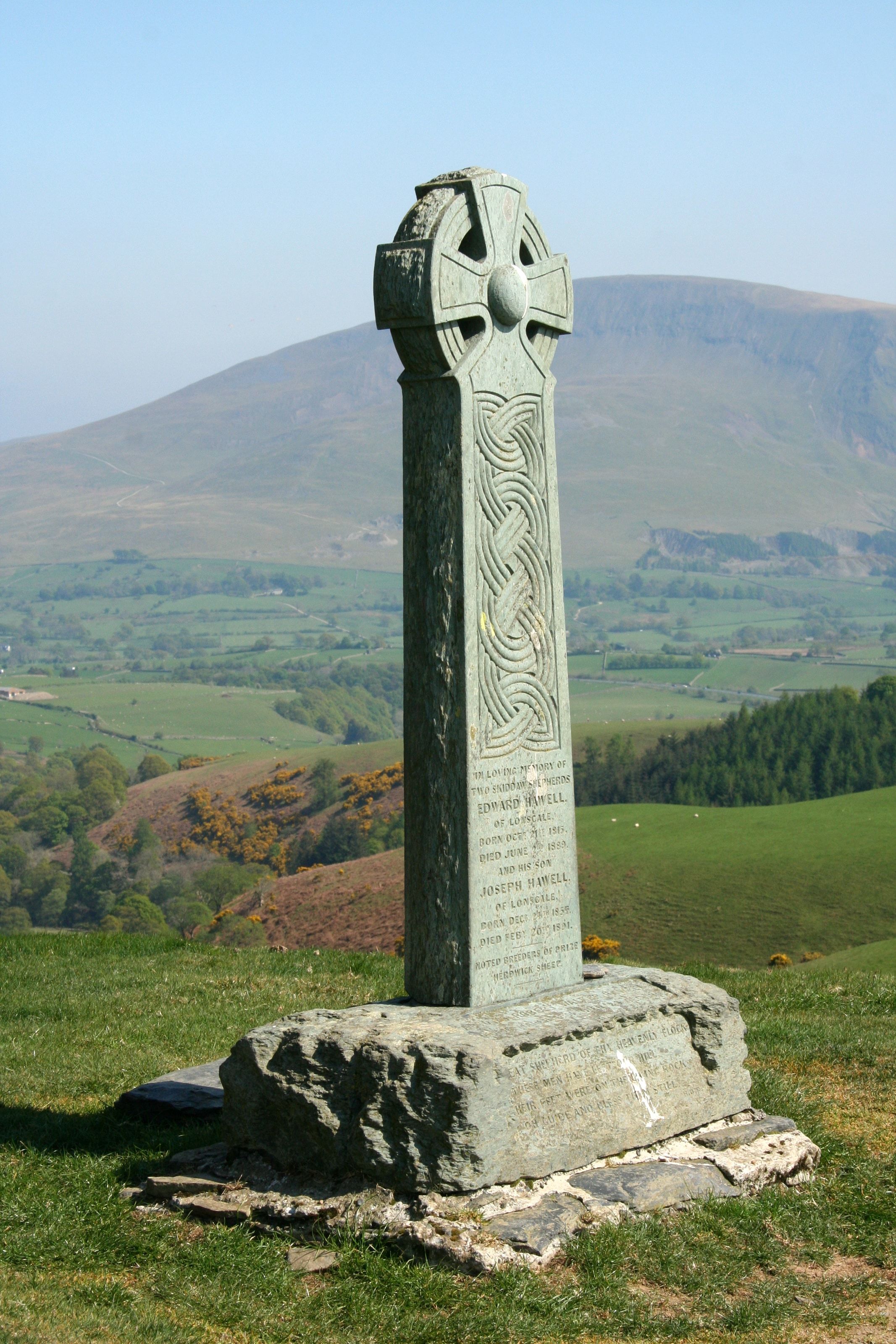 A tall carved stone monument standing above a green valley
