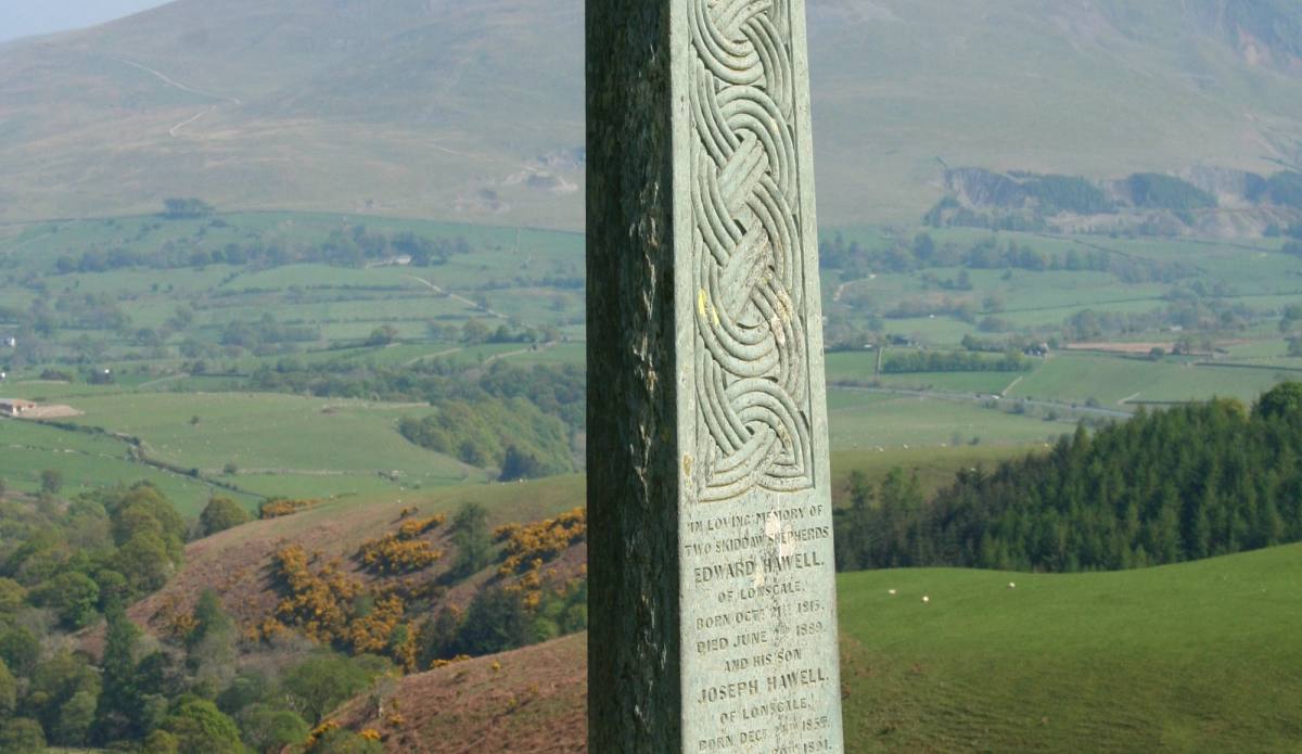 A tall carved stone monument standing above a green valley