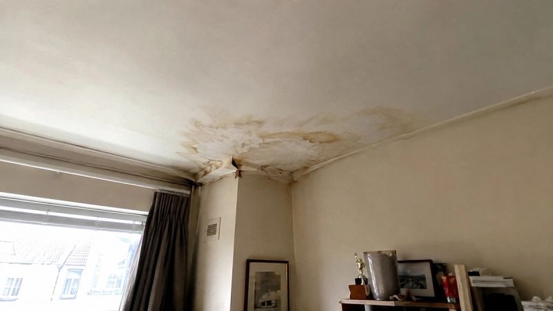 Bulging, water-stained ceiling patch in a London flat, damage caused by a leak from the flat above