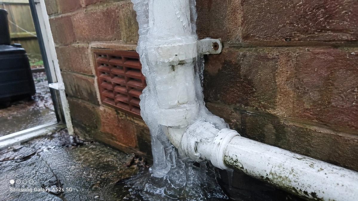 Close-up of a frozen condensate pipe with ice buildup on a UK rental property's exterior wall