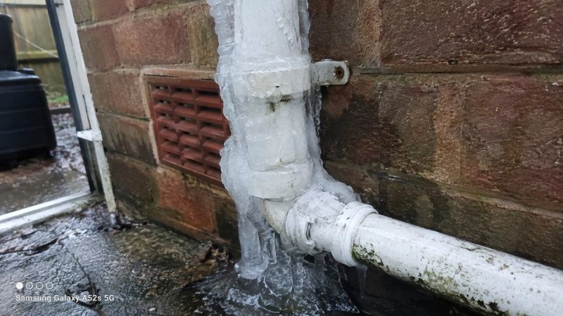 Close-up of a frozen condensate pipe with ice buildup on a UK rental property's exterior wall