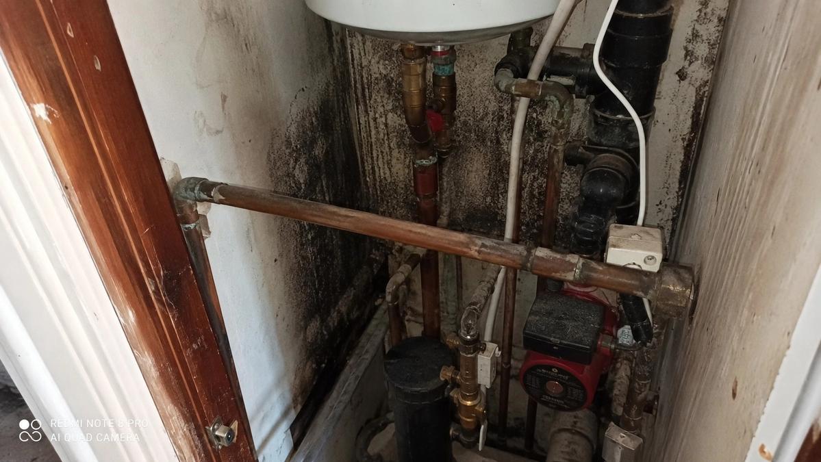 Damp, stained pipework in a UK boiler cupboard showing signs of a hidden water leak