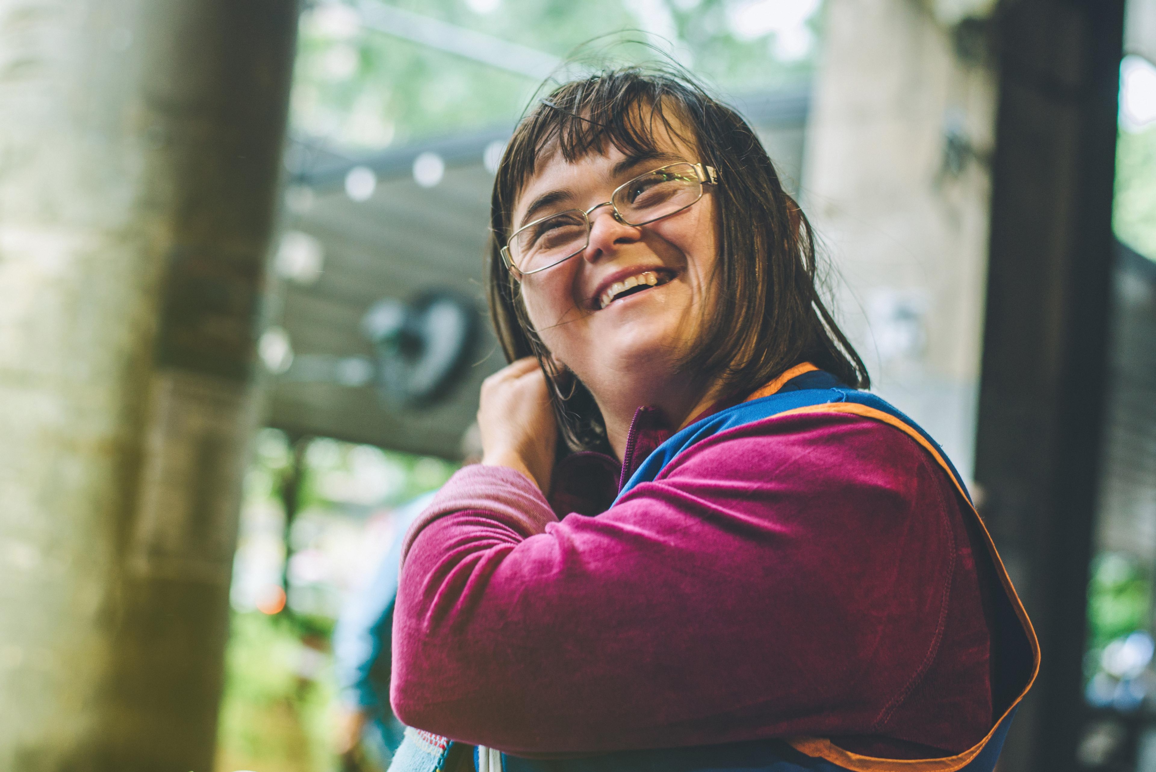 Liceulice vendor Nataša, who has Down Syndrome, smiles while wearing glasses and her vendor uniform of blue and orange