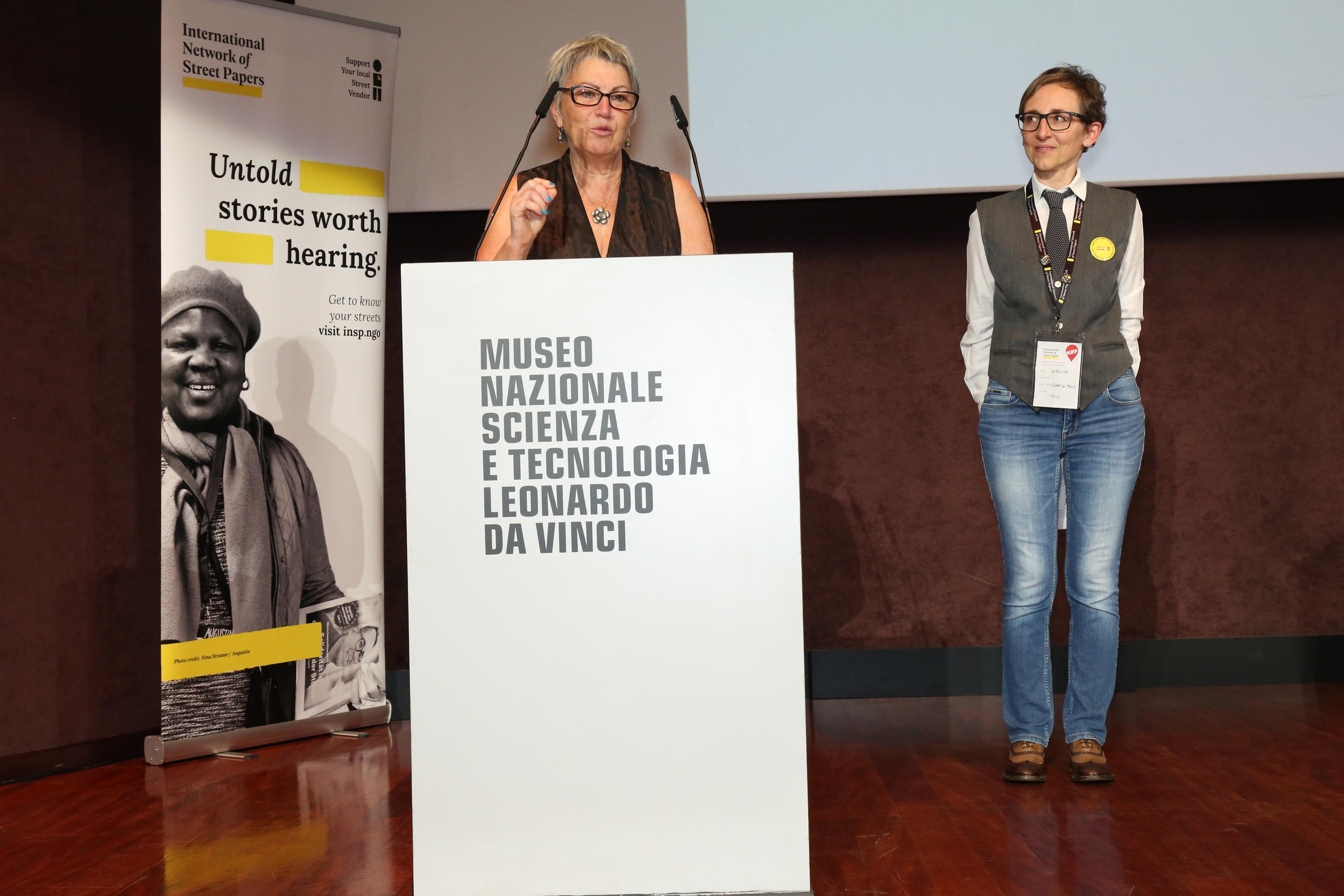 Two women behind a lectern on stage