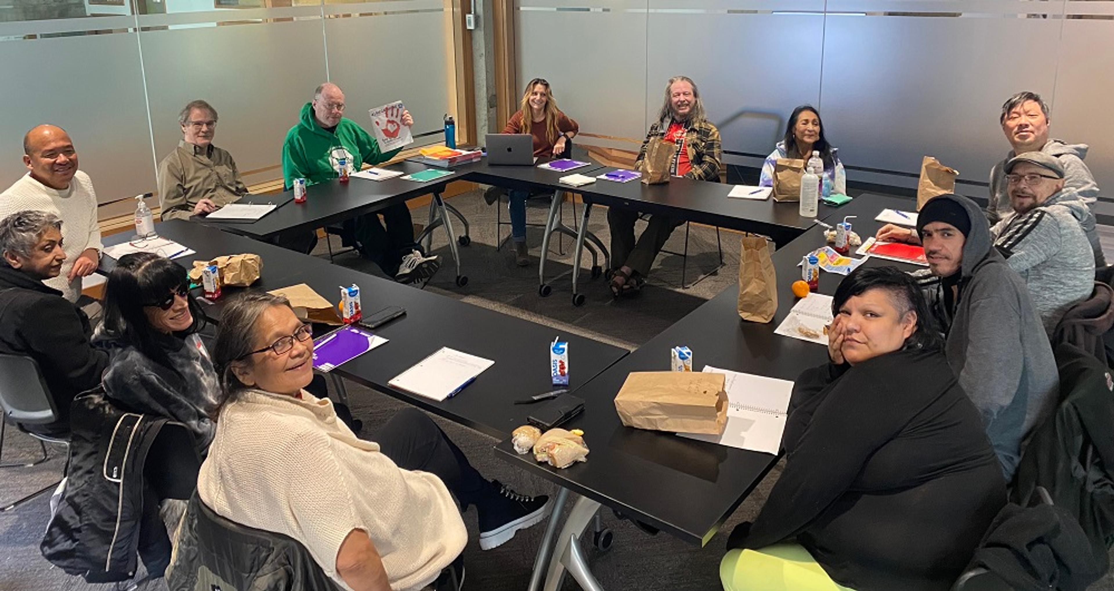 Megaphone vendors and staff sit round a table at a meeting of The Shift editorial newsroom