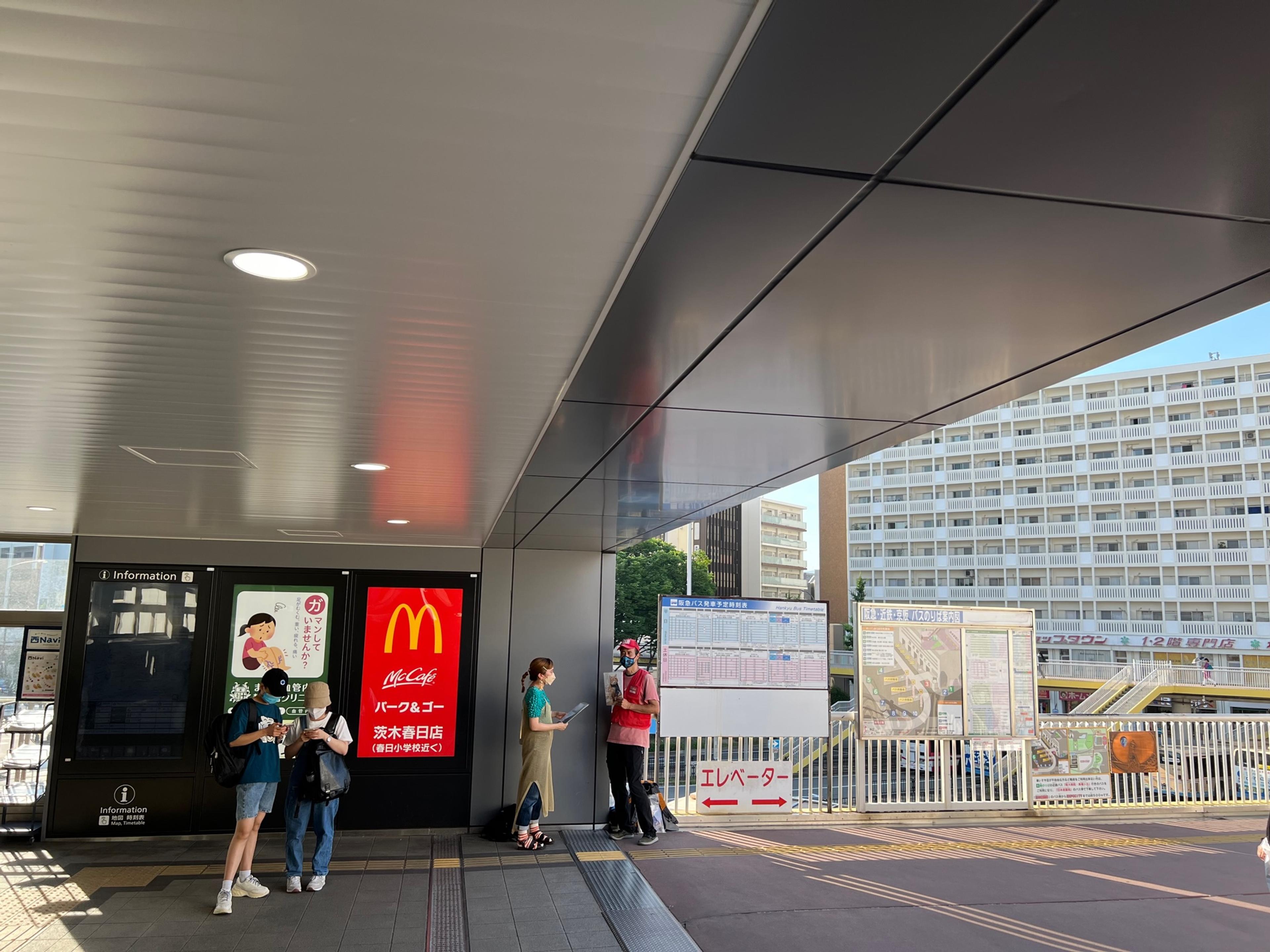 A street paper vendor sells a magazine to a customer next to the entrance of a train station