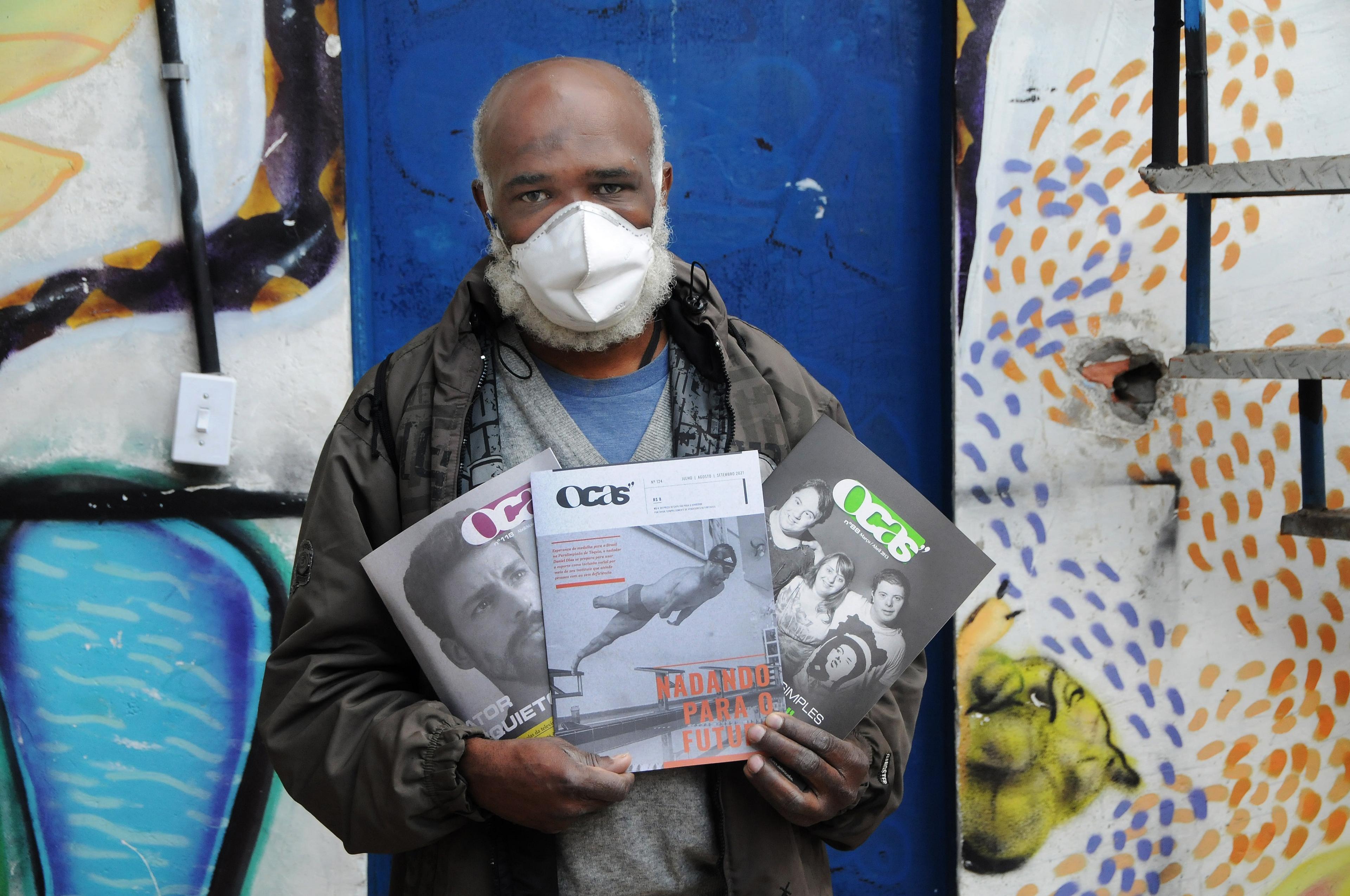 A man wearing a mask holding magazines