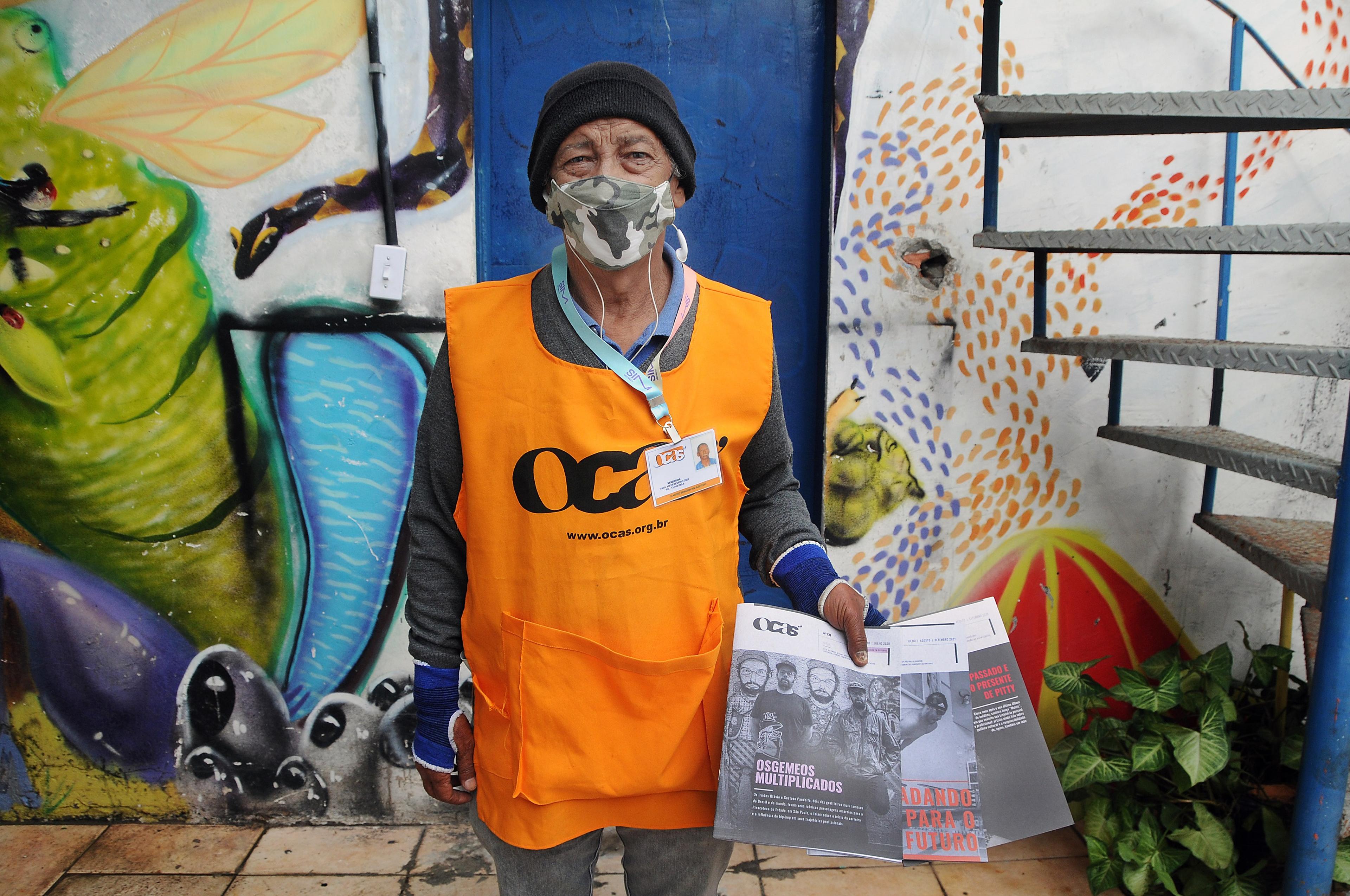 Man wearing orange vest and mask with magazines