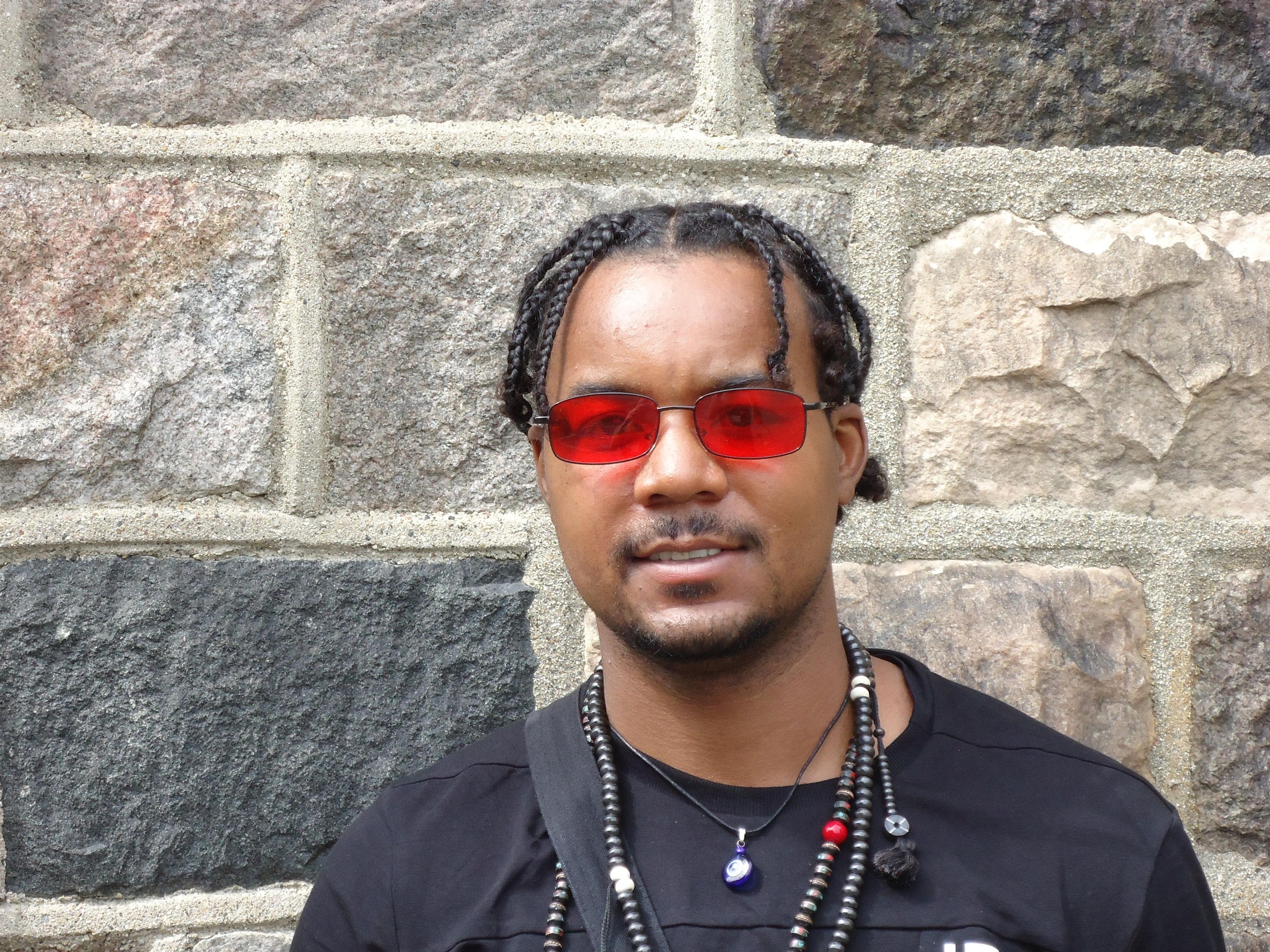 Man in glasses in front of brick wall