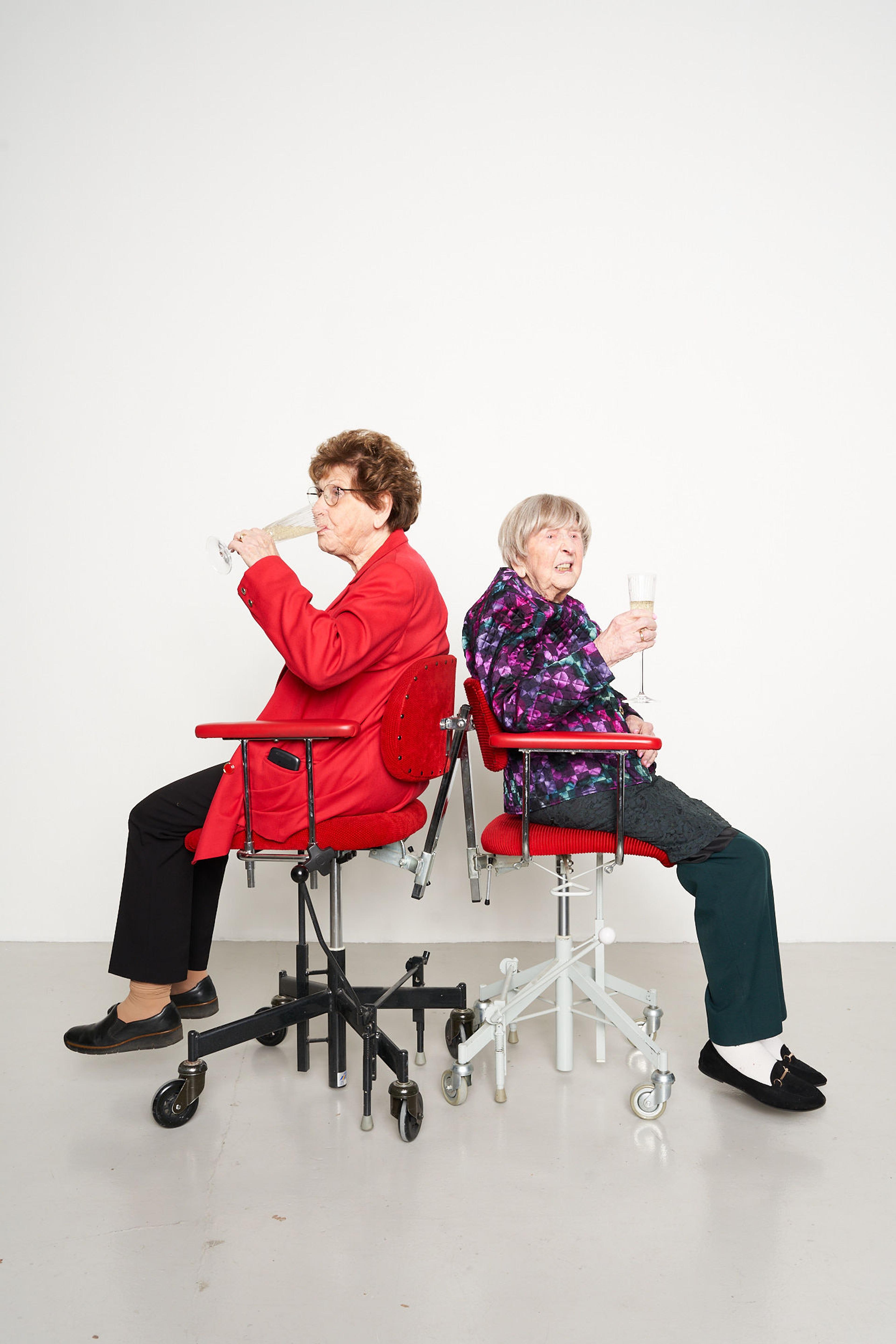 Two elderly women in chairs drinking fizz