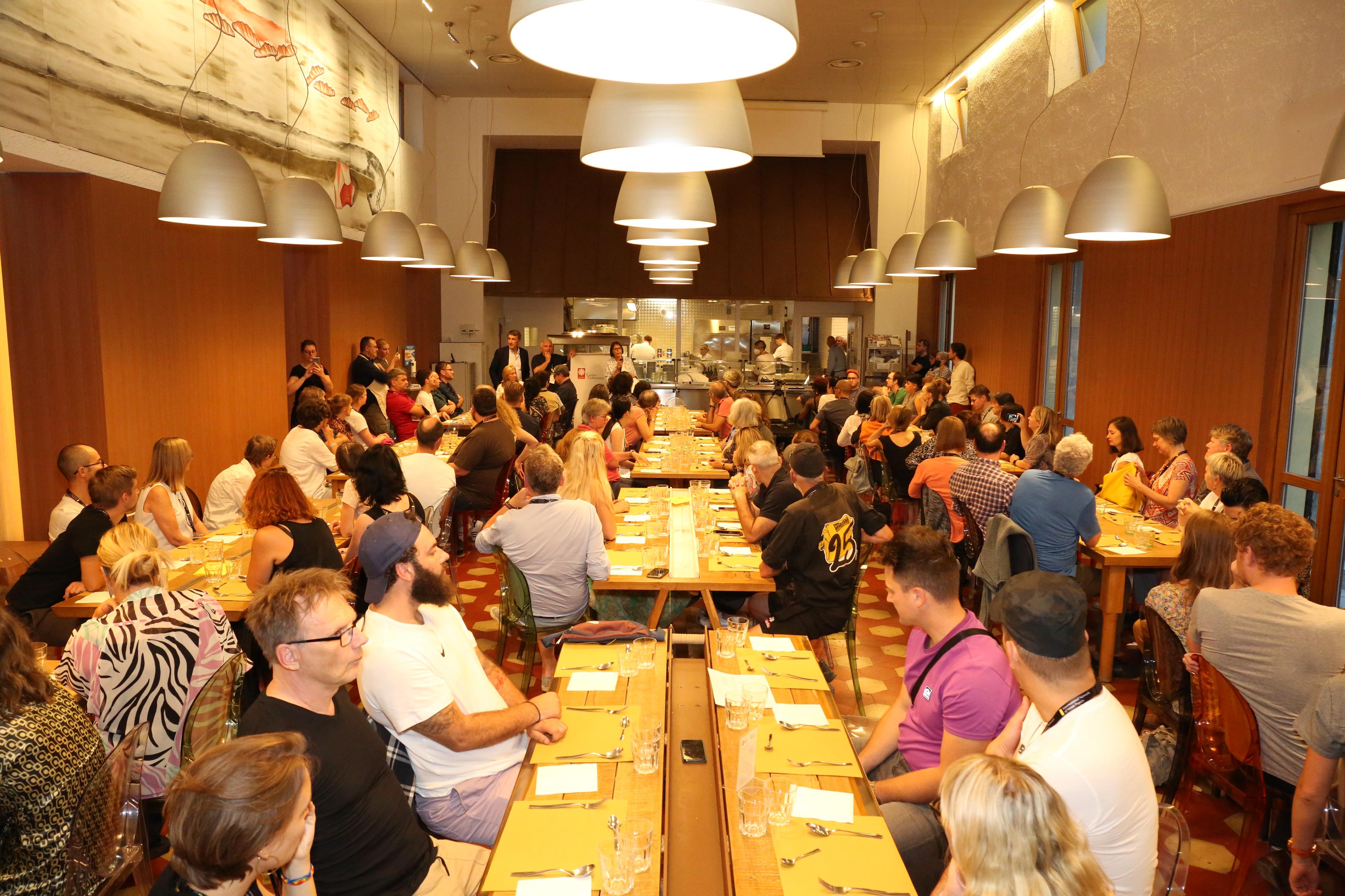 People eat at long tables in a community kitchen