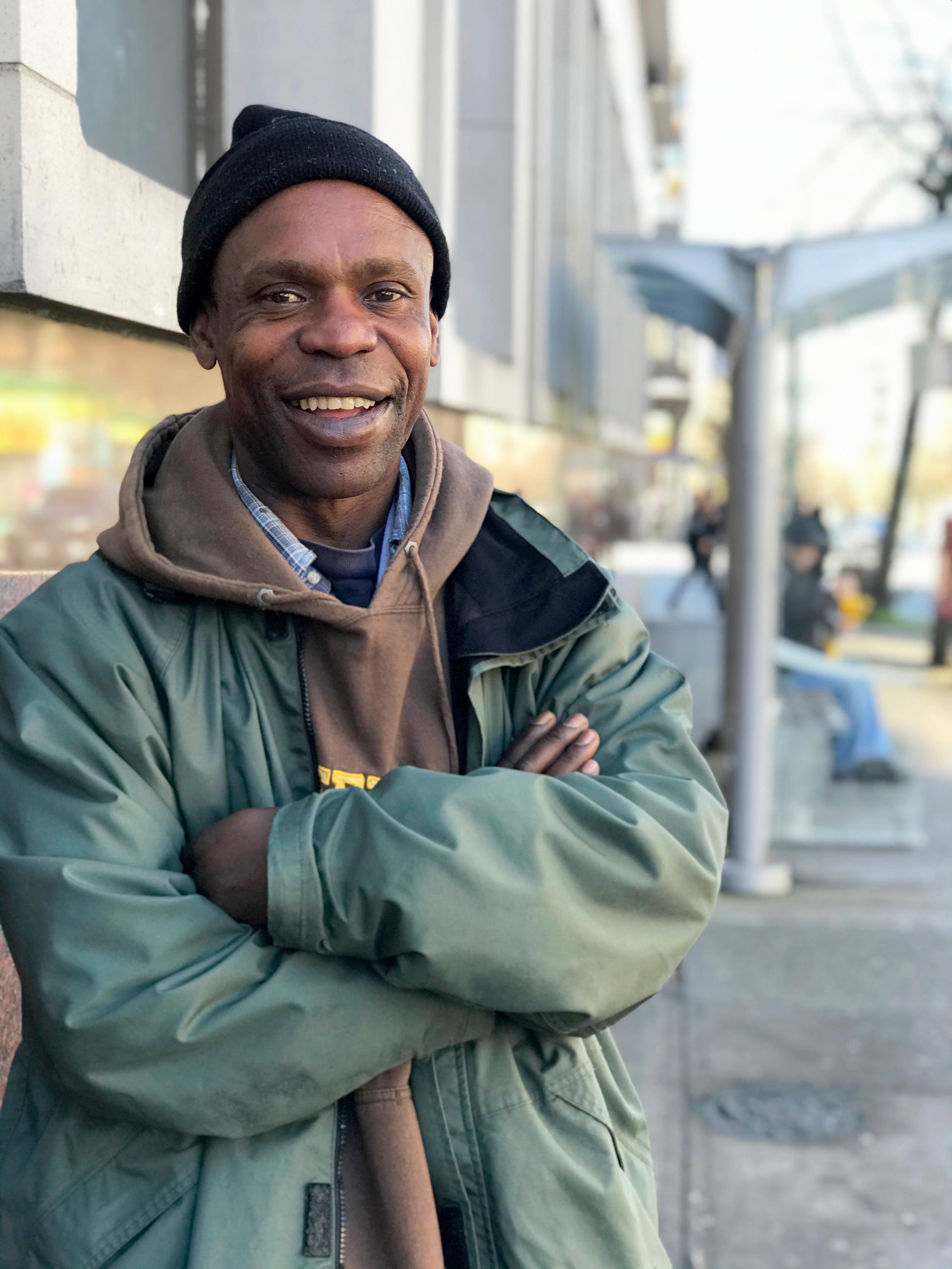 Paul Shawdover faces the camera wearing a beanie hat, a hoodie and an anorak. His arms are folded and he's smiling.