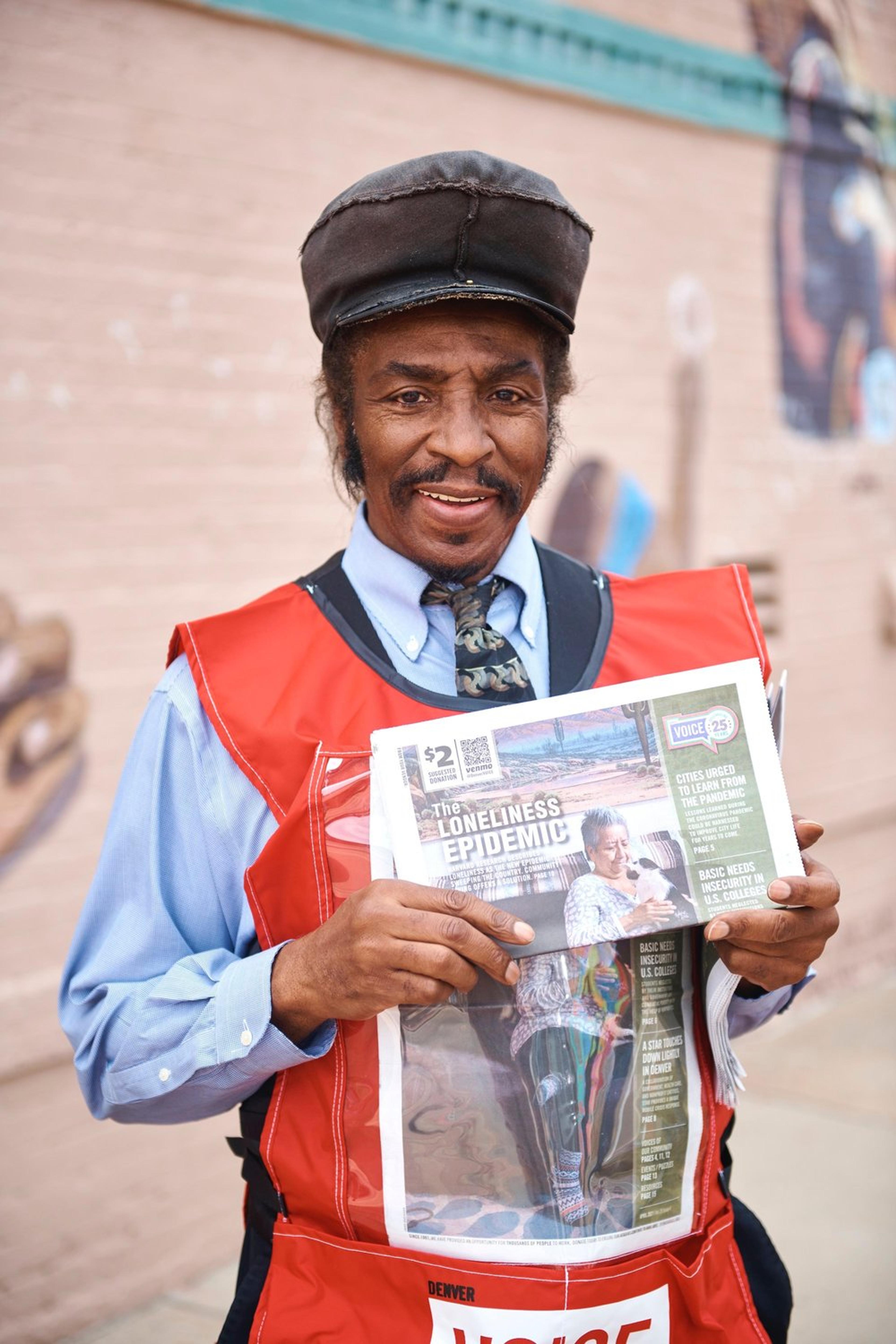 man holding Denver Voice street paper