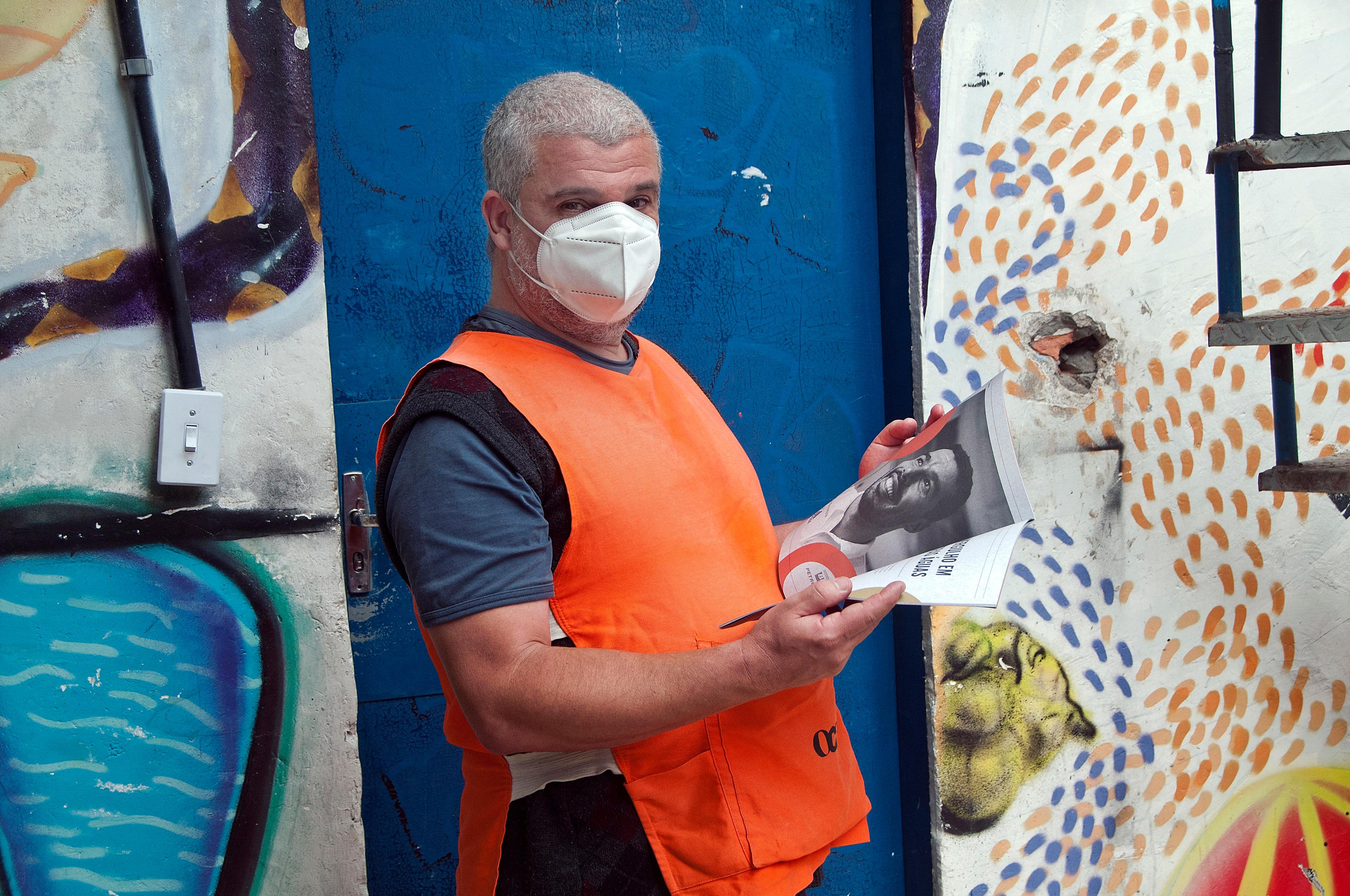 Man in orange vest and mask with a magazine