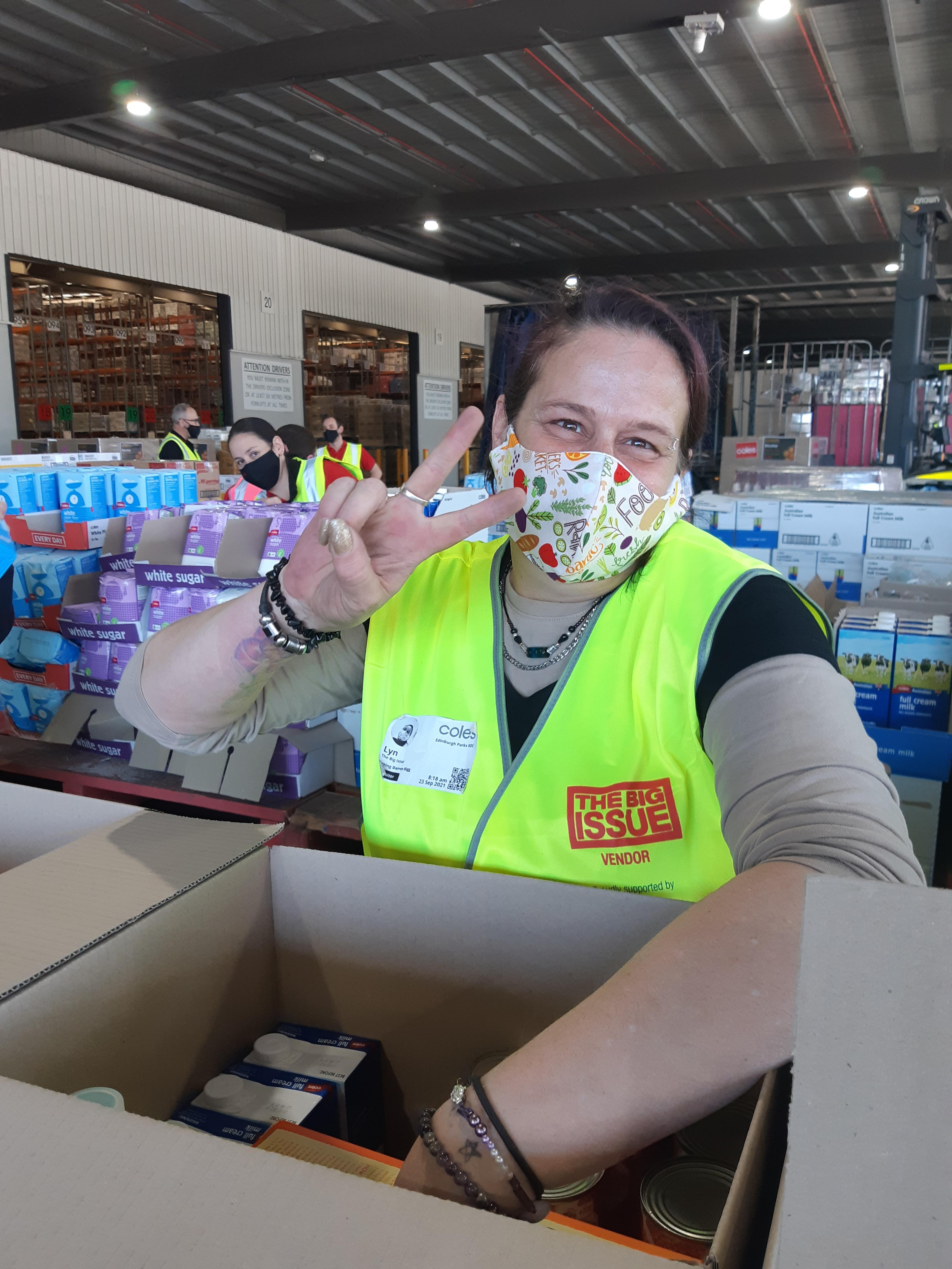 Lyn, who earns an income via The Big Issue Australia's Women's Workforce wears a mask as she packs boxes