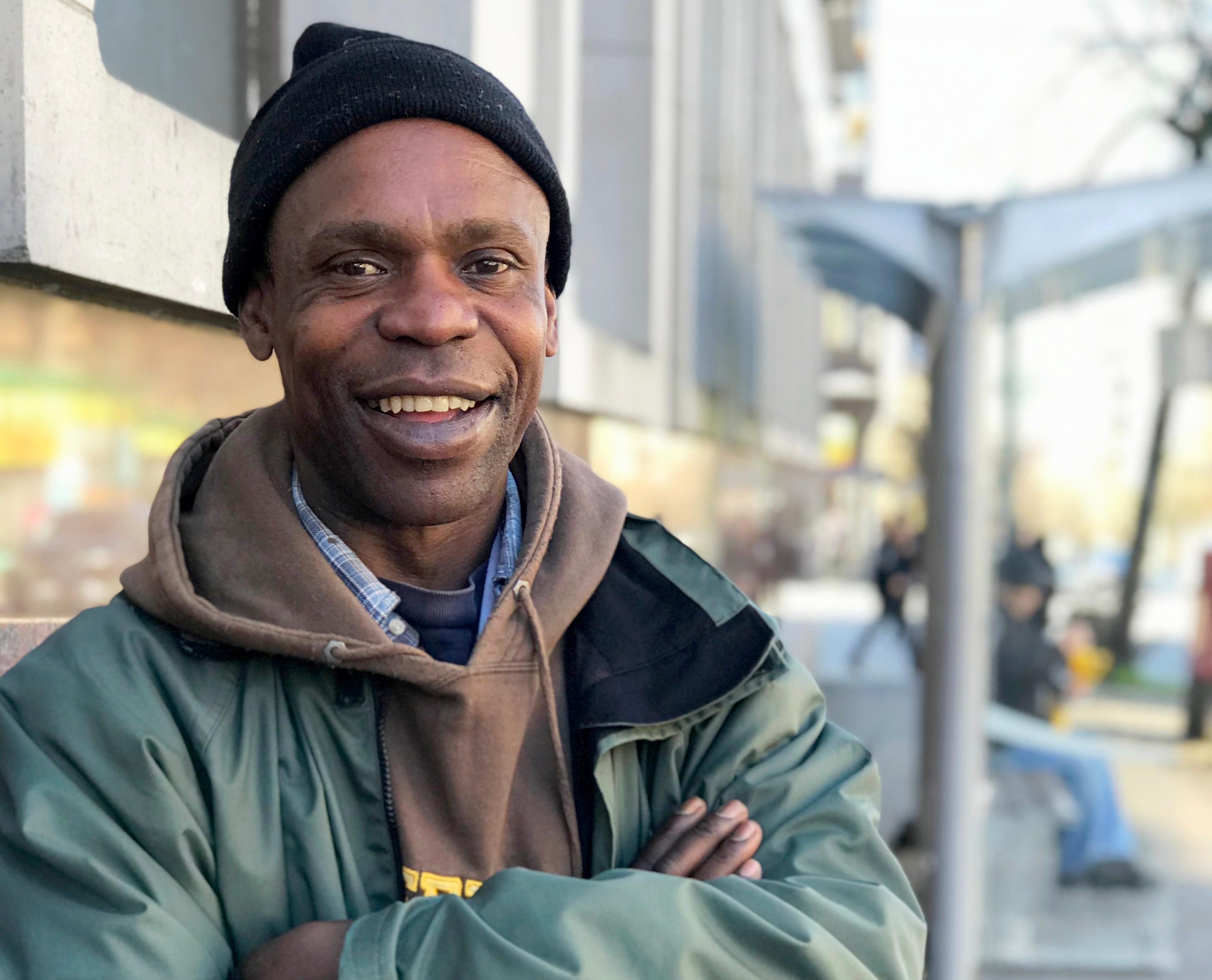 Paul Shawdover faces the camera wearing a beanie hat, a hoodie and an anorak. His arms are folded and he's smiling.