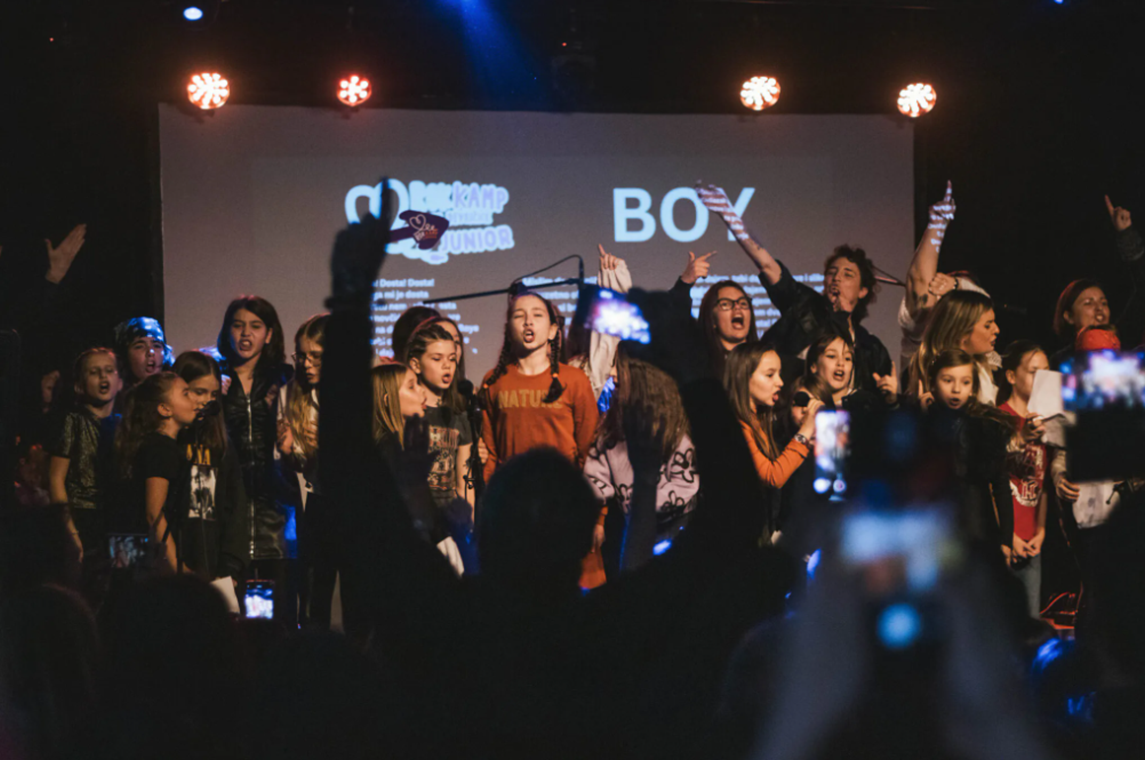 a group of young girls singing on a stage