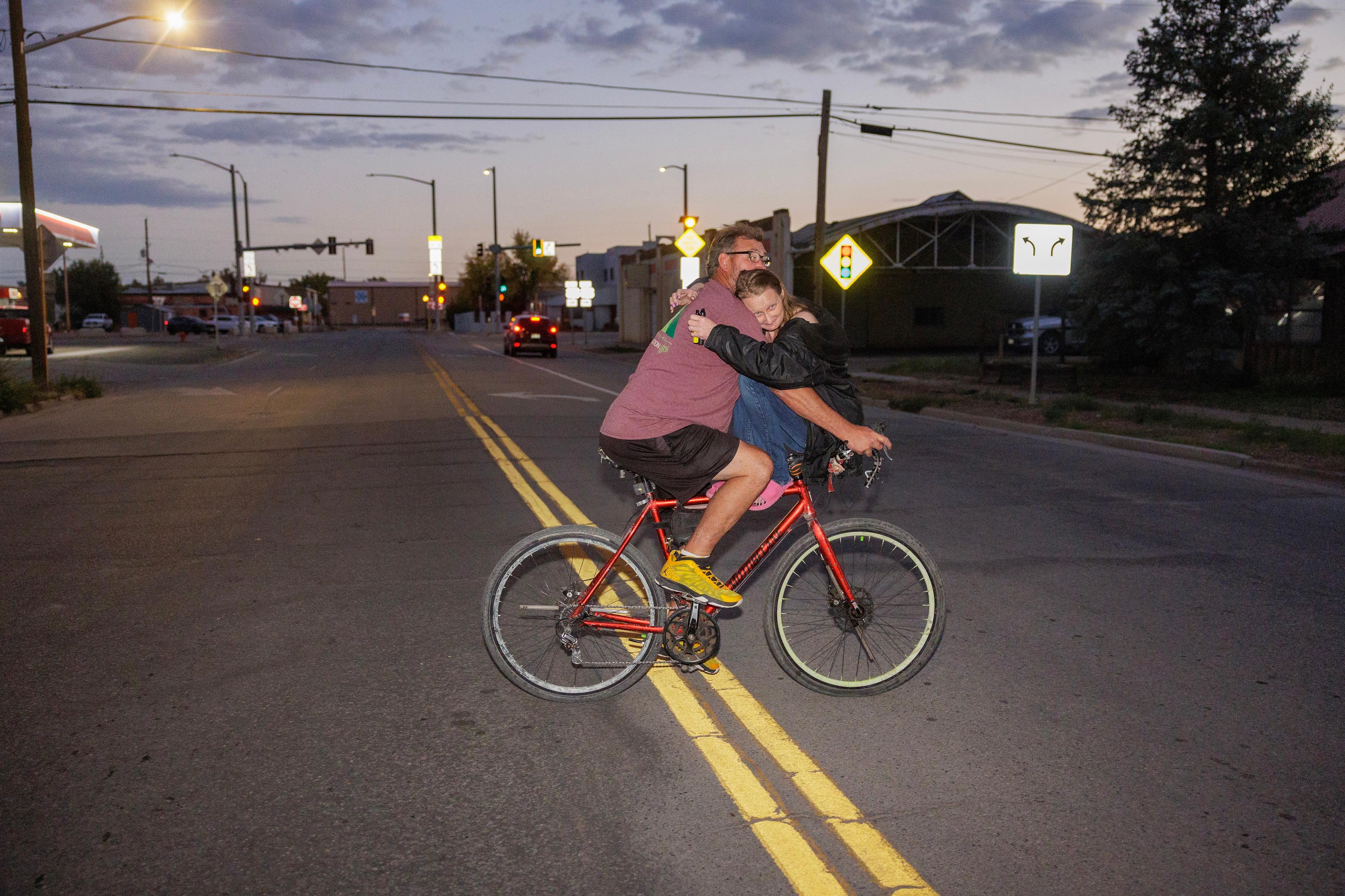 a man riding a bike, while a female sits in front and holds on to him