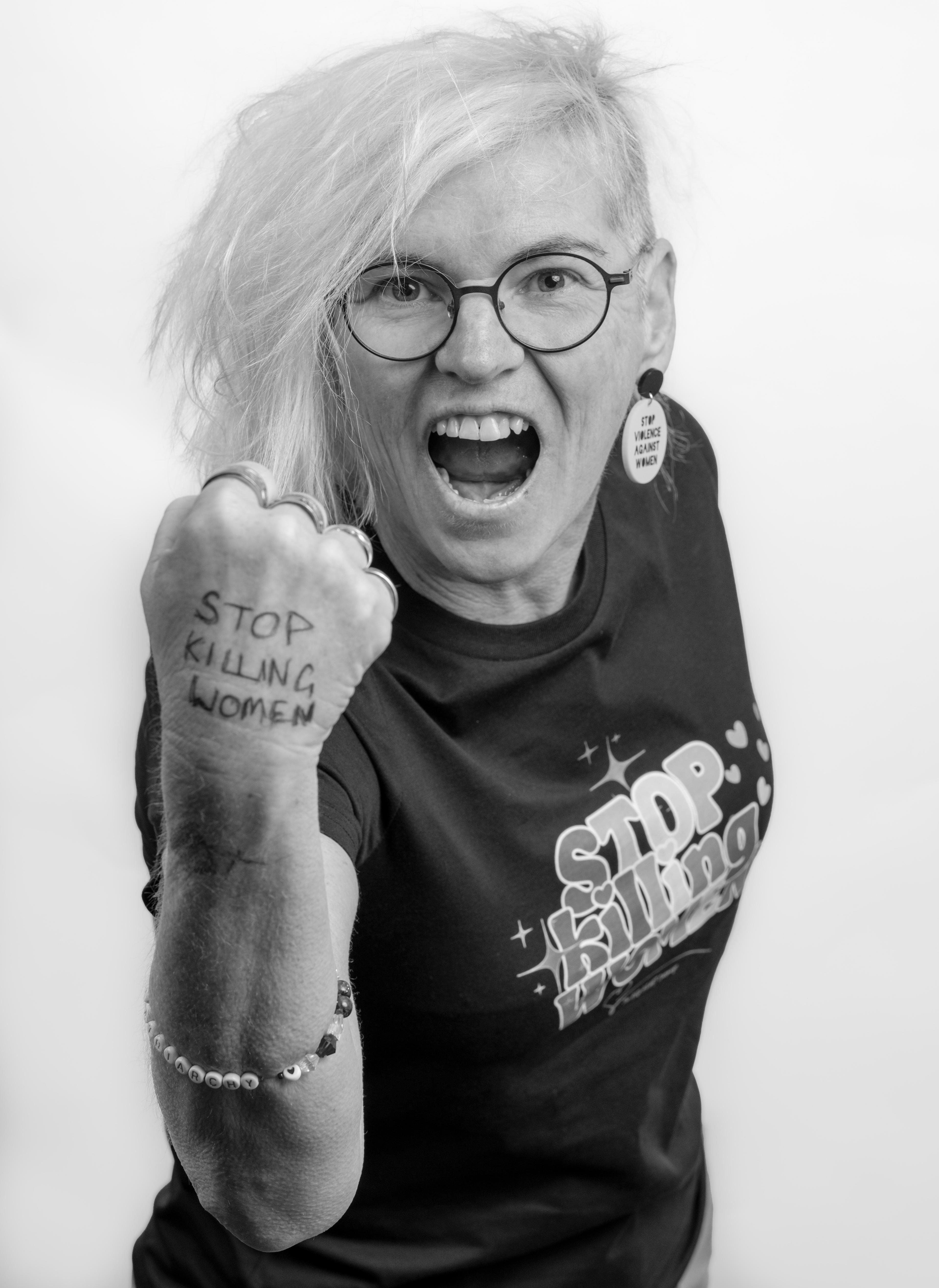 a black and white photo of a woman facing the camera with her fist raised