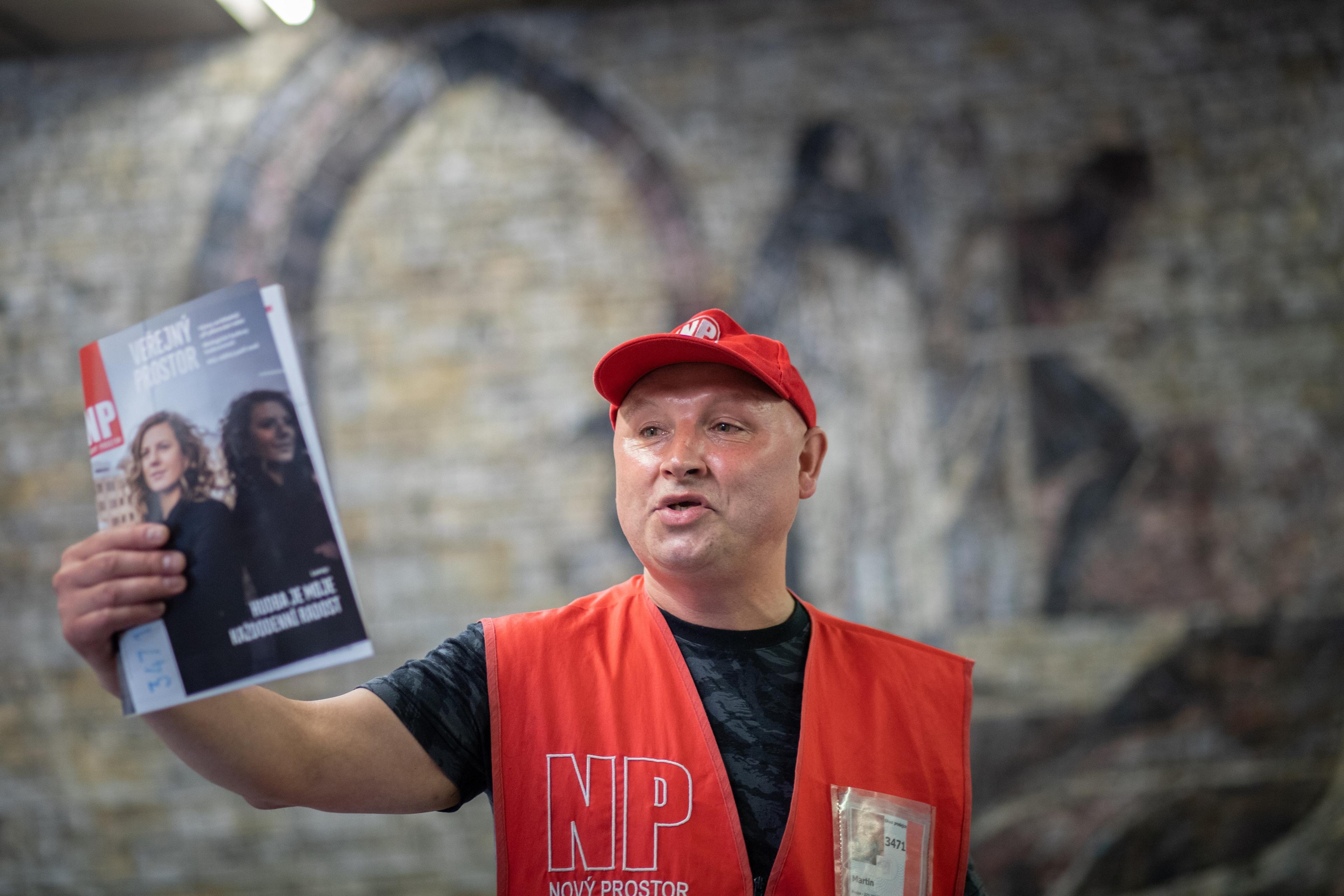 Man in red cap and vest holds up magazine