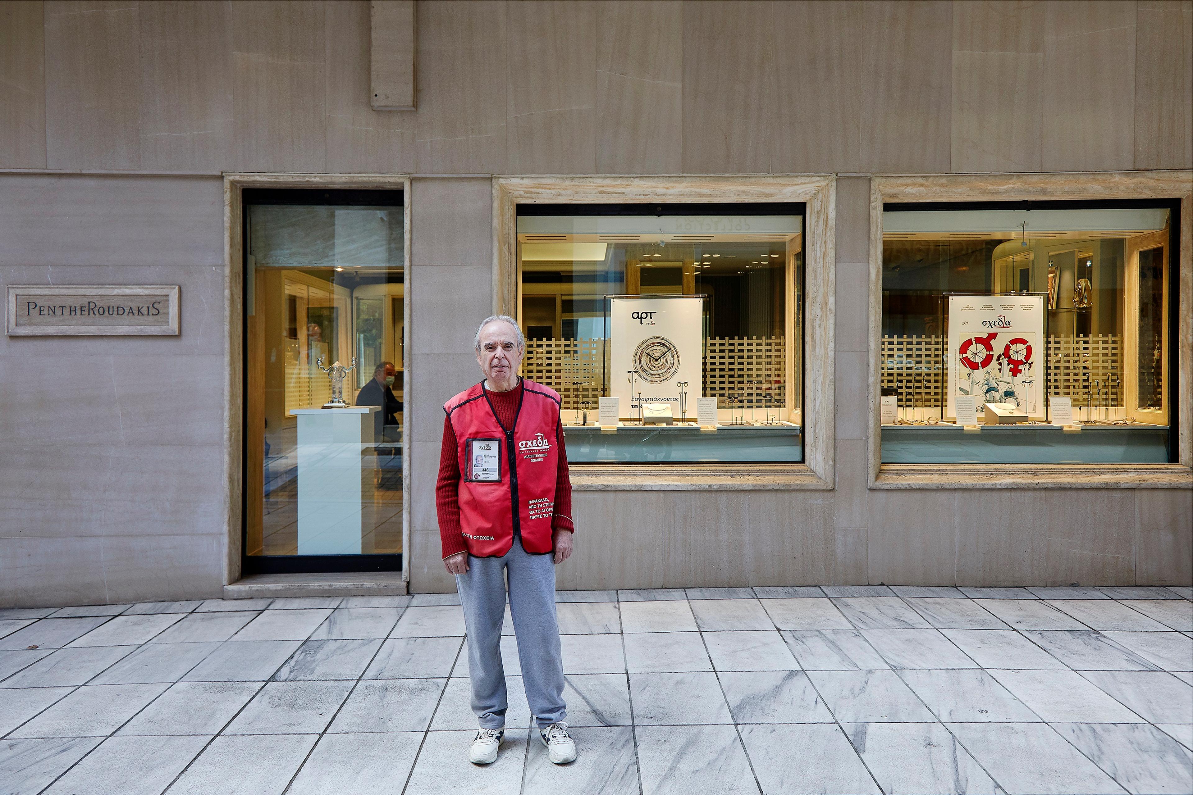 A man in a red vest stands in front of a store