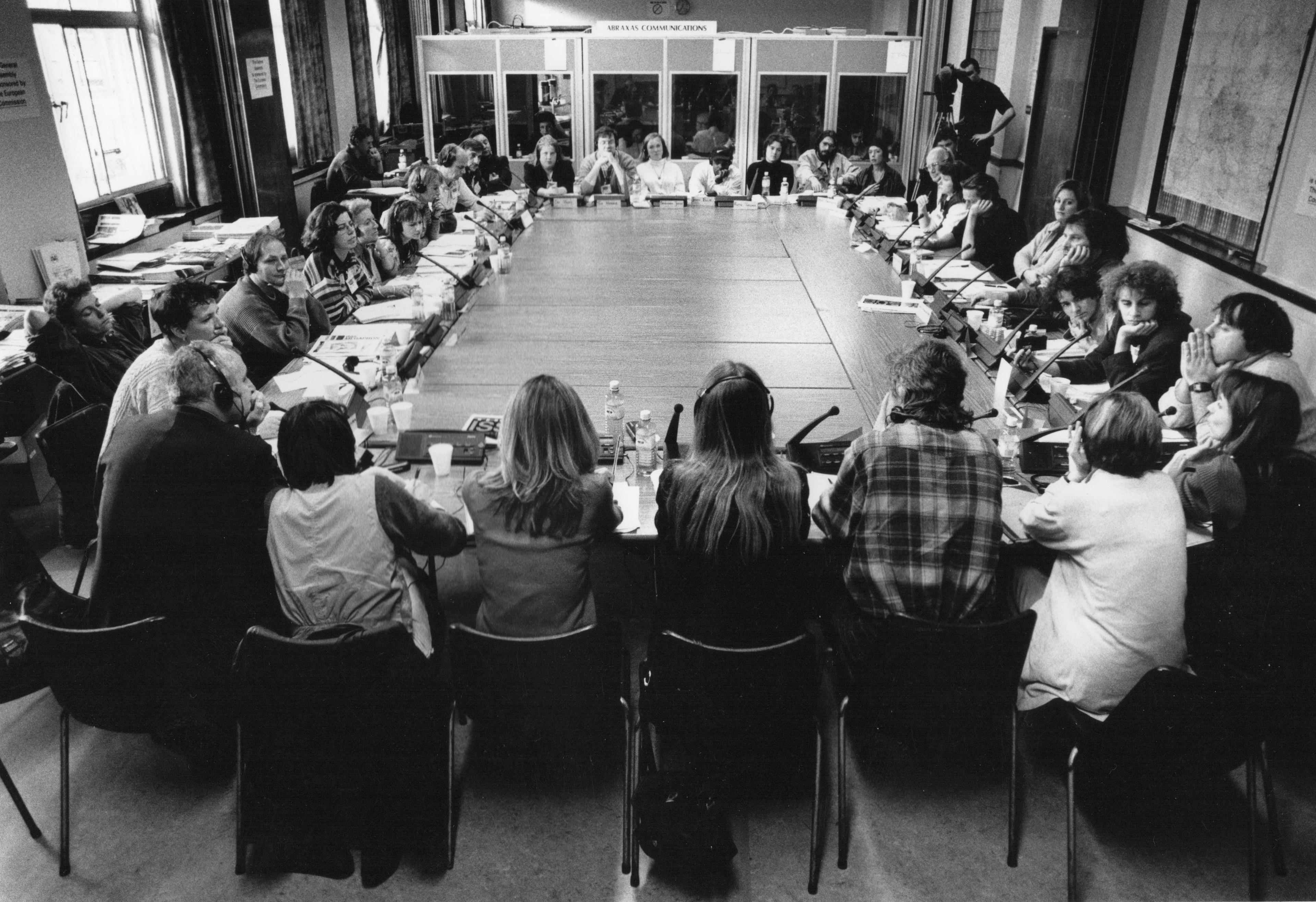 Street paper staff sitting around a table. Translation booths in the background