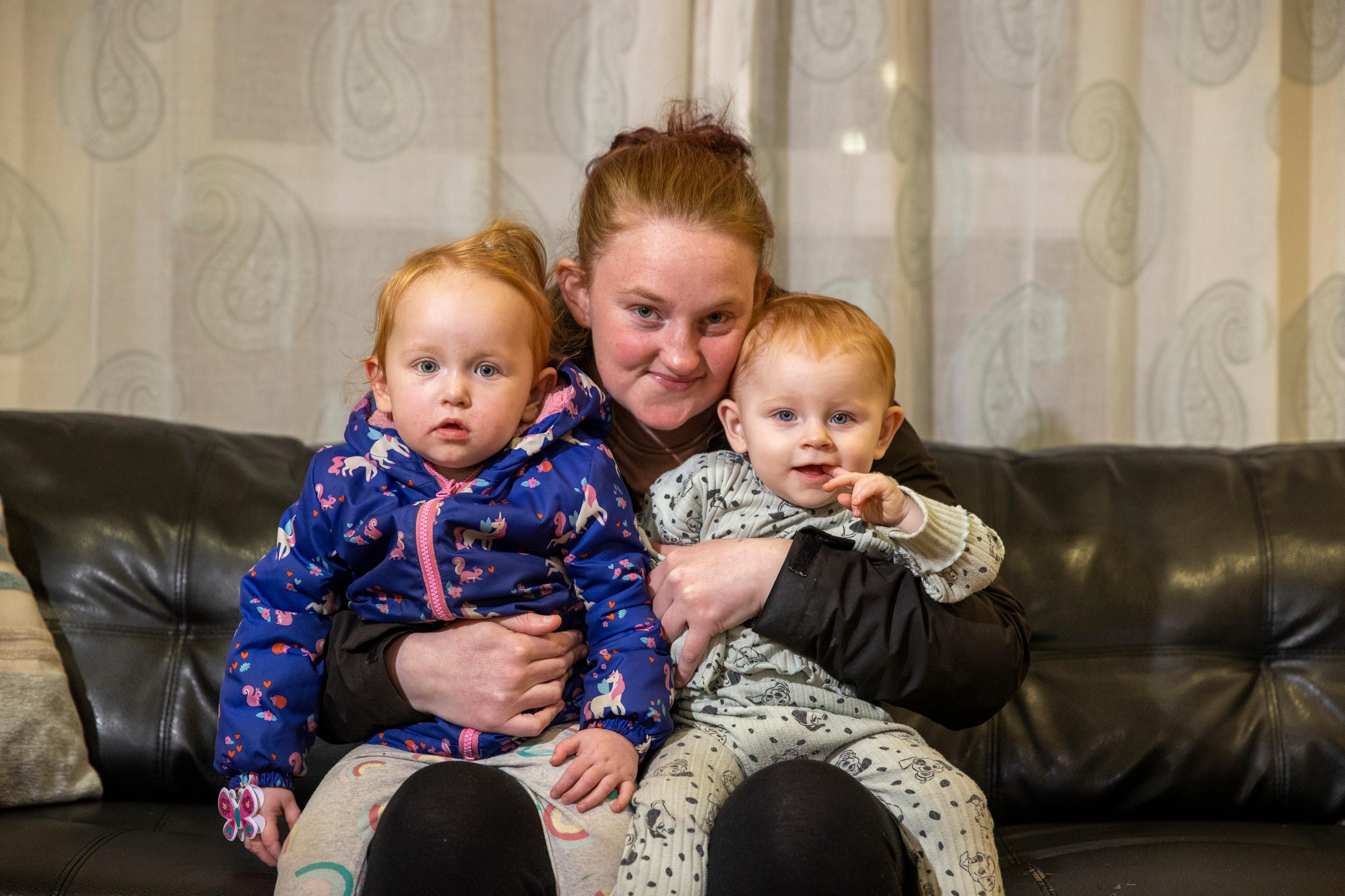 a woman sitting on a sofa holding two children