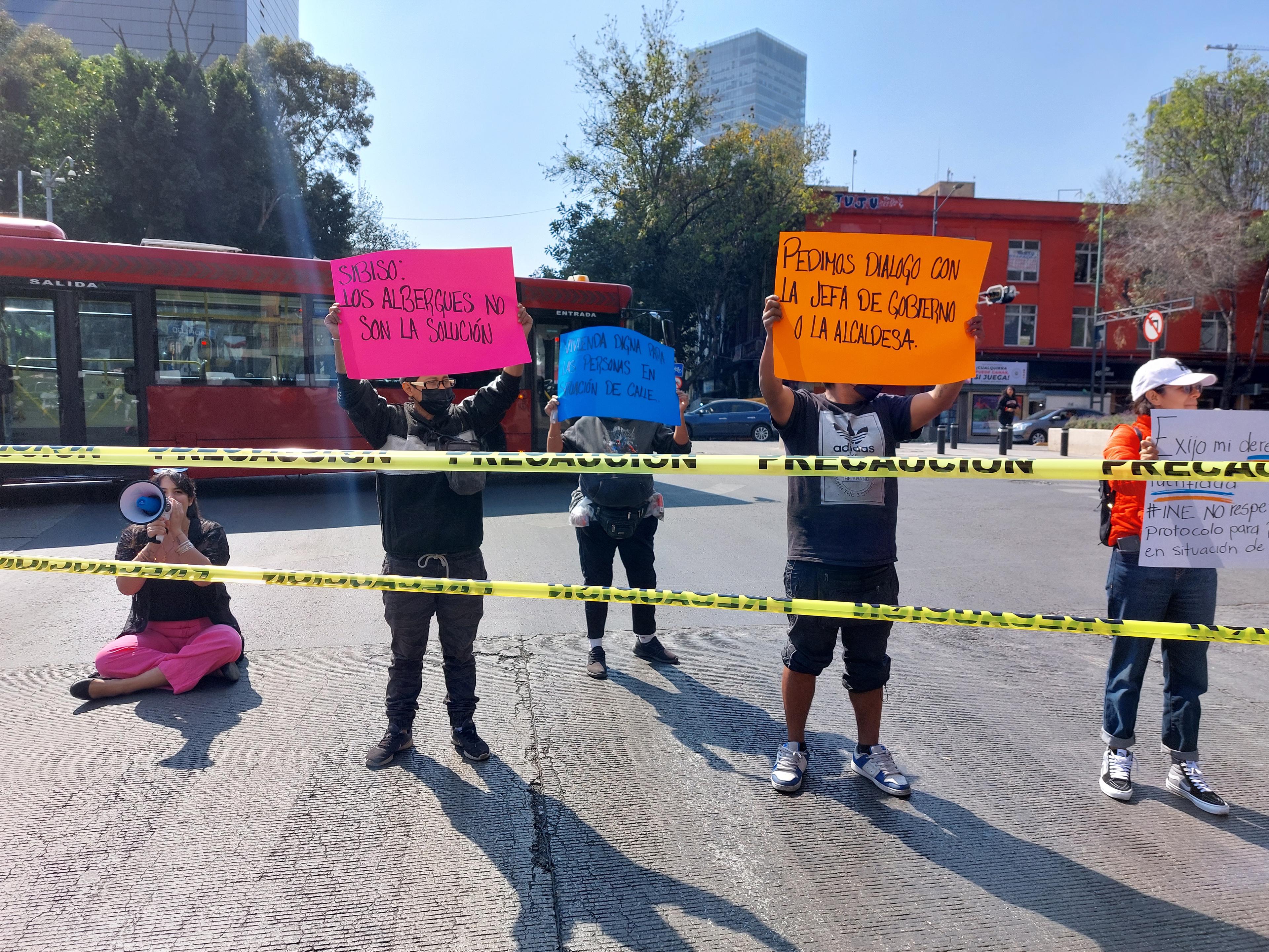 Protestors for homeless rights in Mexico City hold up various placards and shout through a megaphone