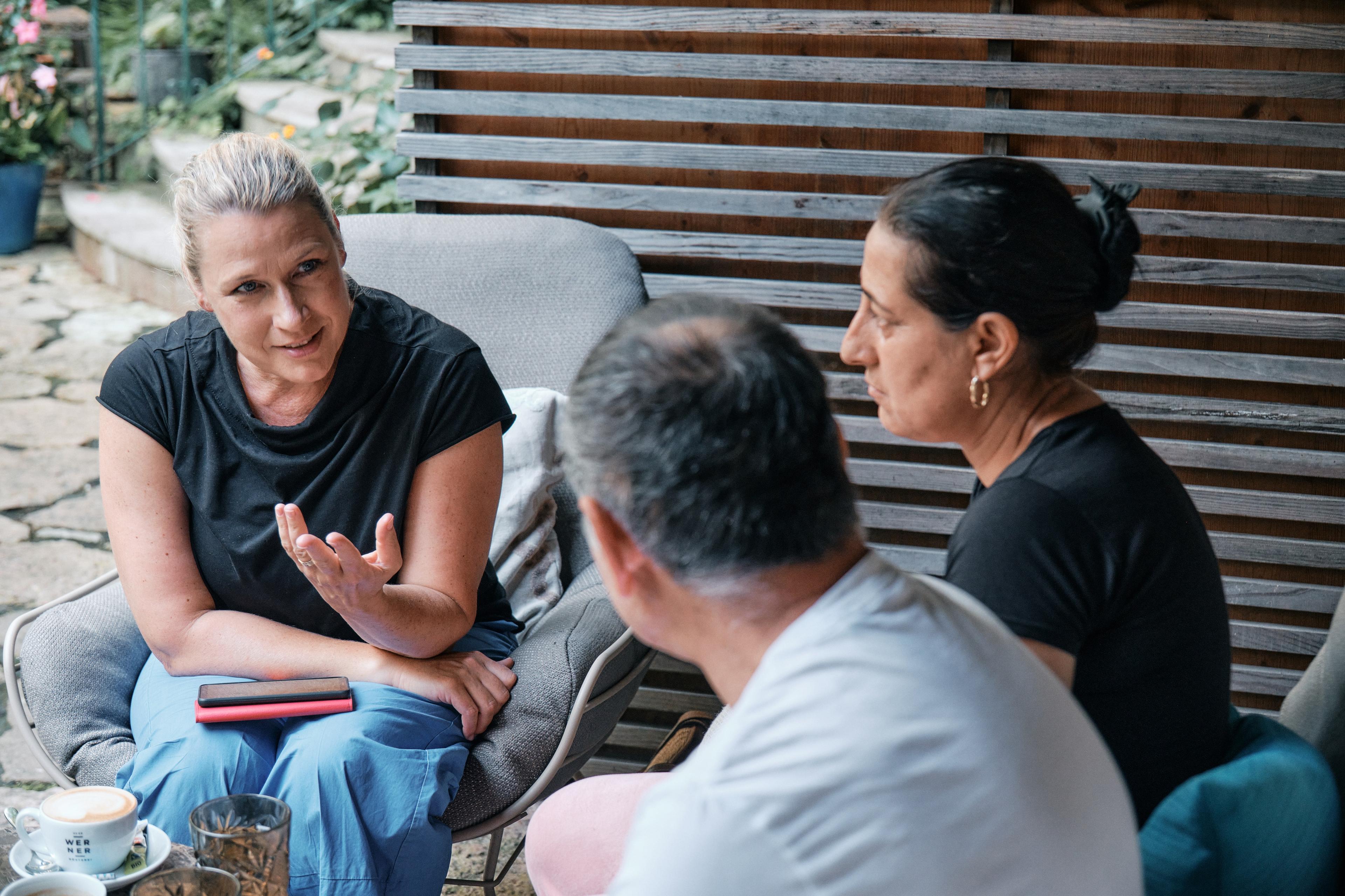 three people sitting on armchairs in conversation