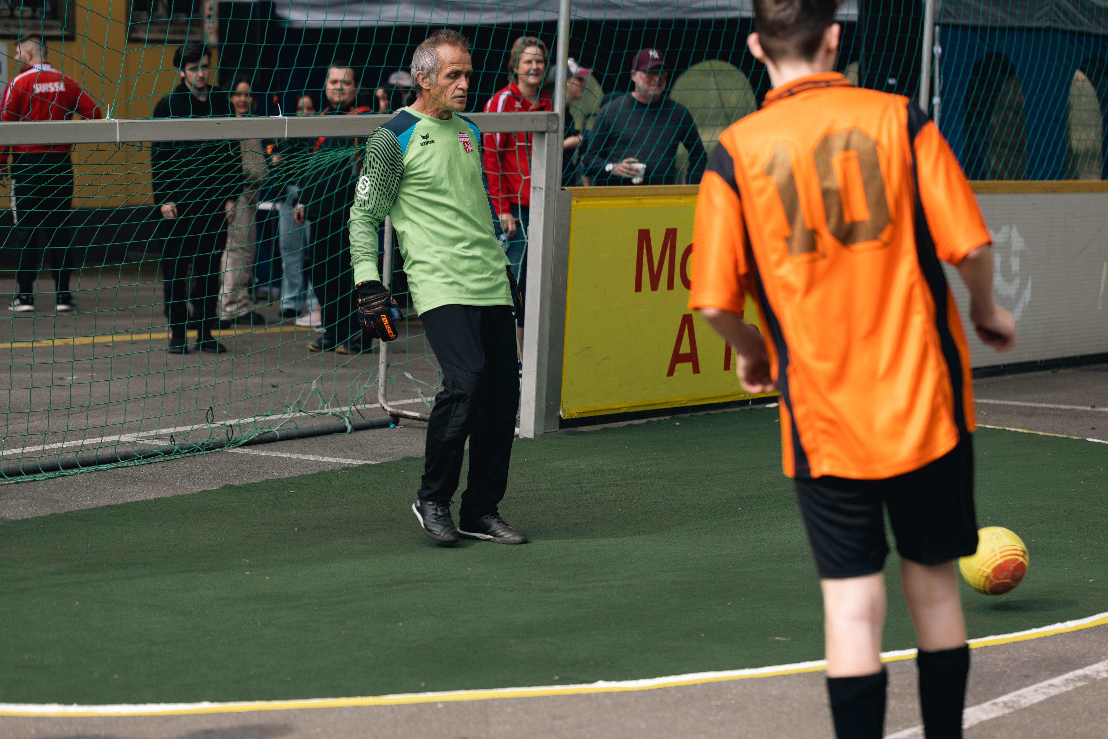 Swiss street soccer team member Heini Hassler wears green standing in goal during a match.