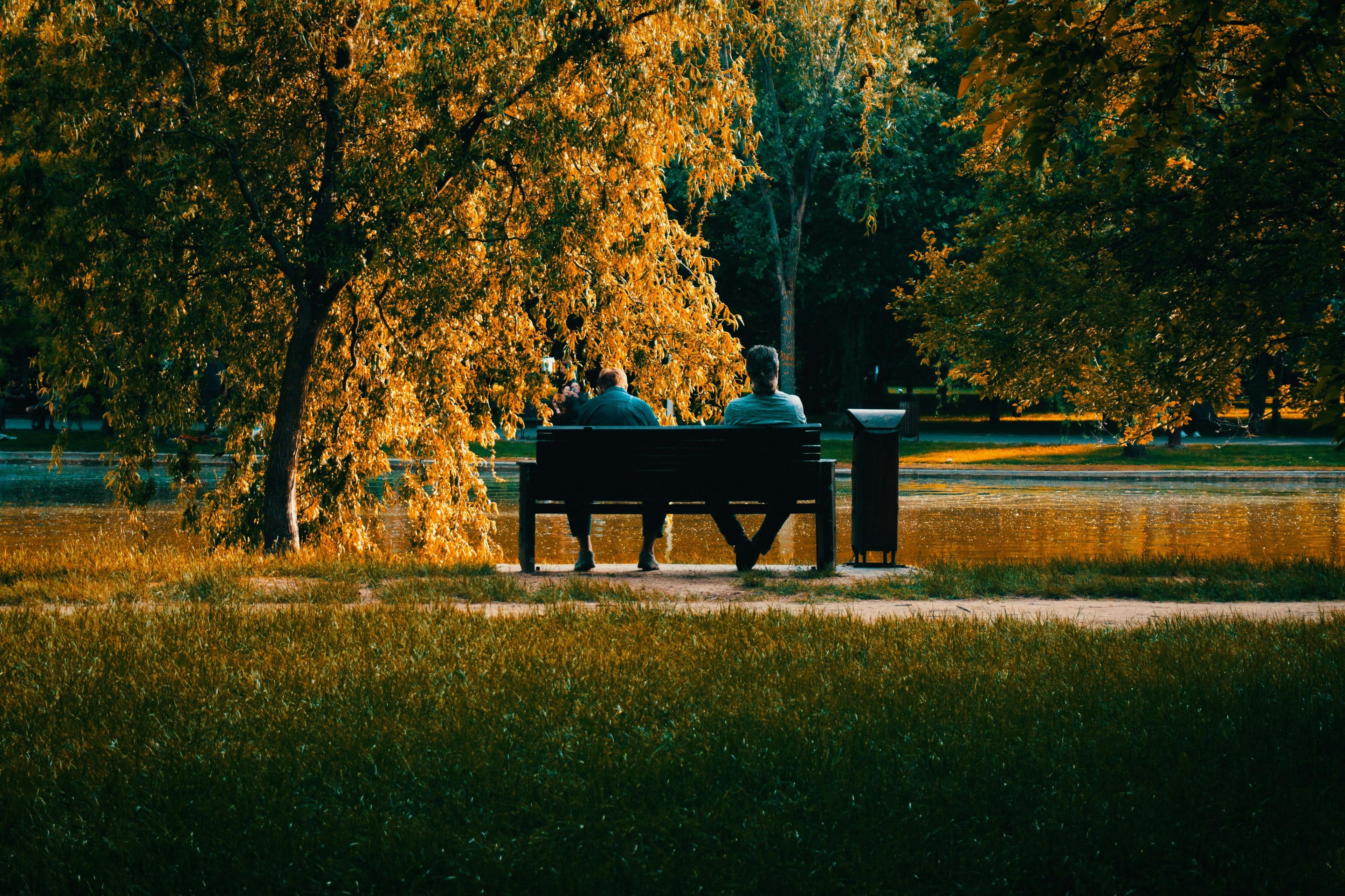 Two men talking on a park bench in autumn
