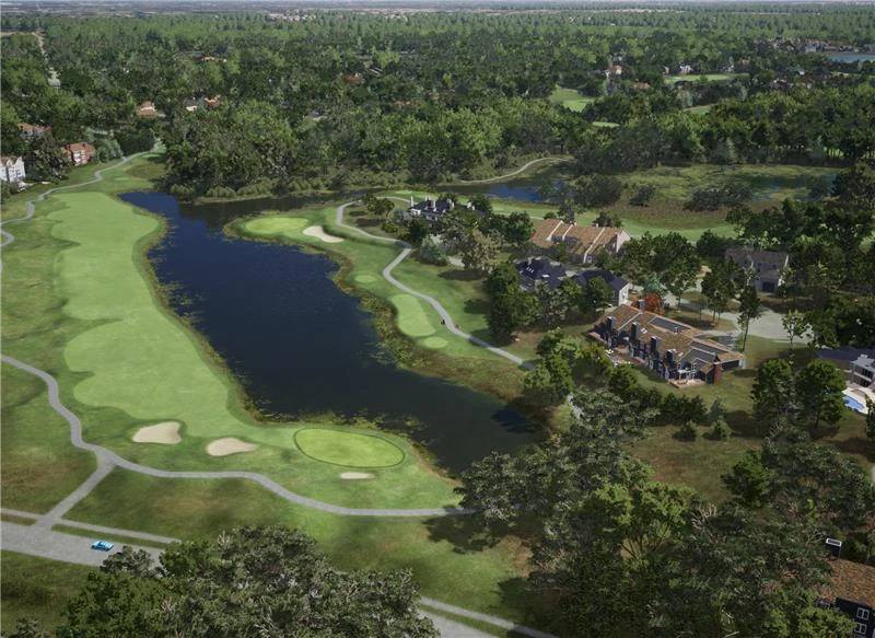Aerial view of a golf course with a long lake, surrounded by houses and dense trees.