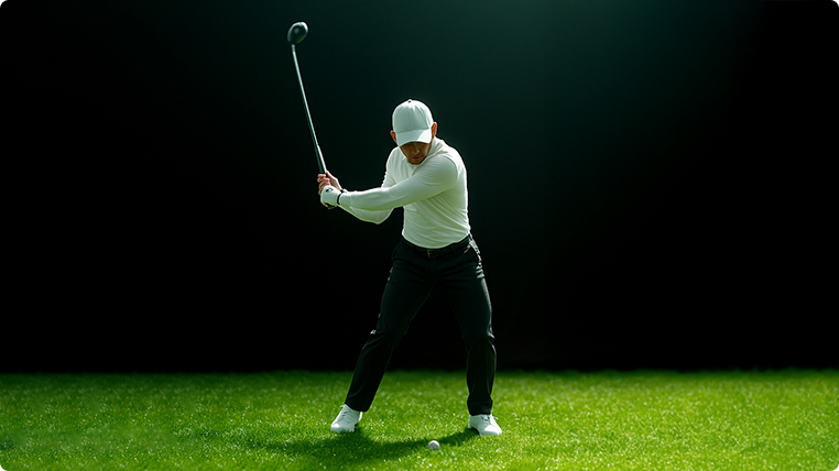 A golfer in a white shirt and cap swings a golf club on a green course with a golf ball on the grass, against a dark background.