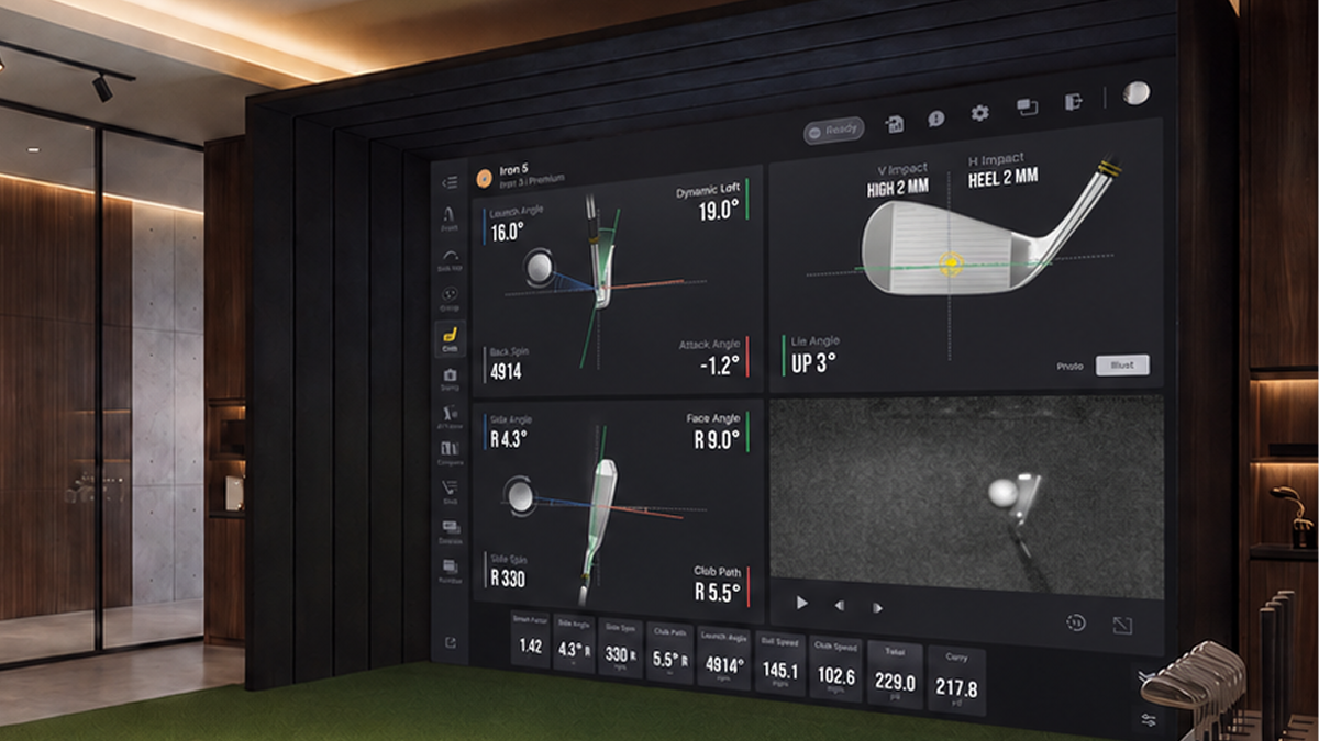 Indoor golf simulator room with a large screen displaying club data, a hitting mat, and golf clubs.