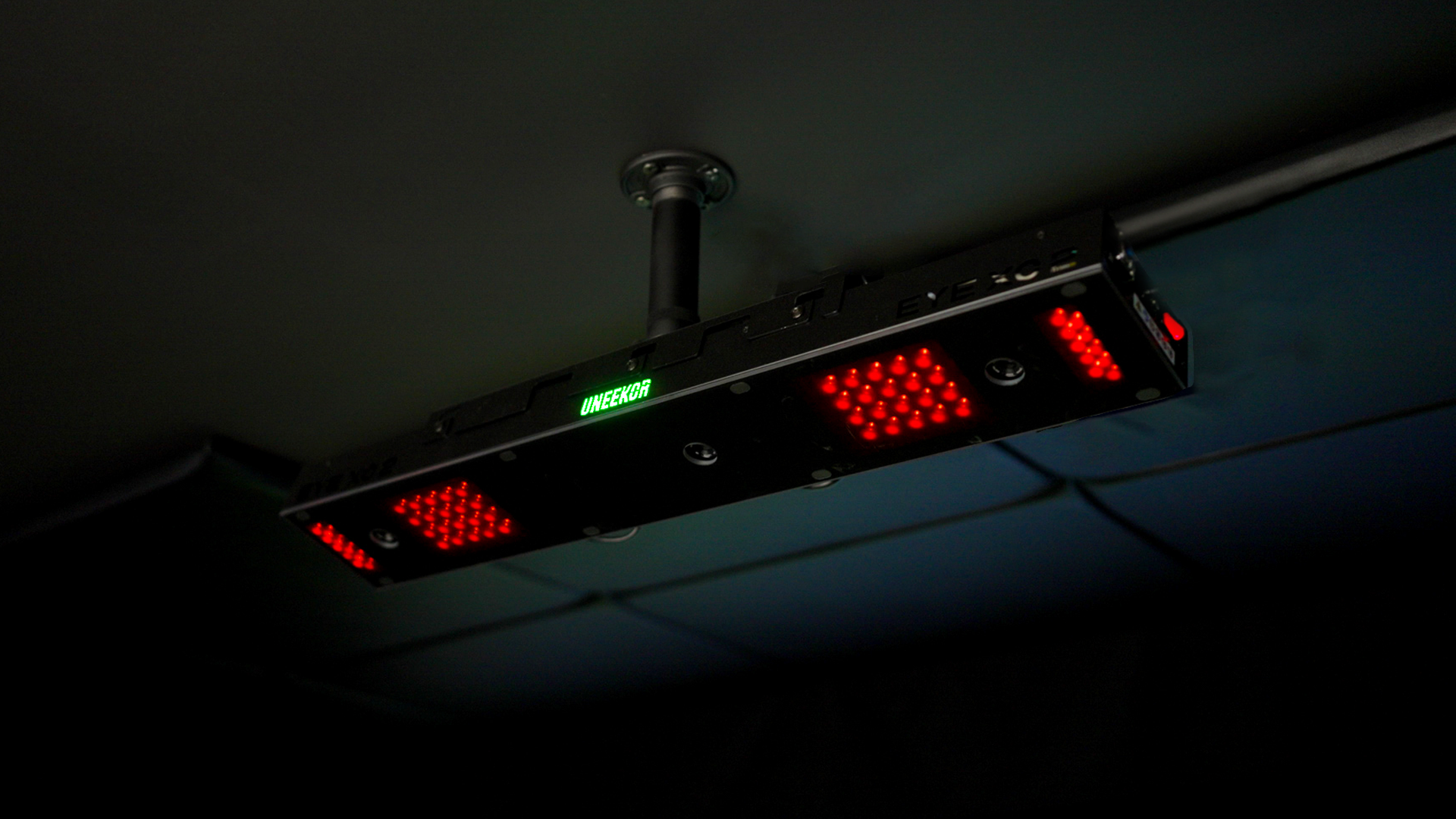A rectangular device with red LED lights and a green "UNSTEADY" display hangs from a dark ceiling.