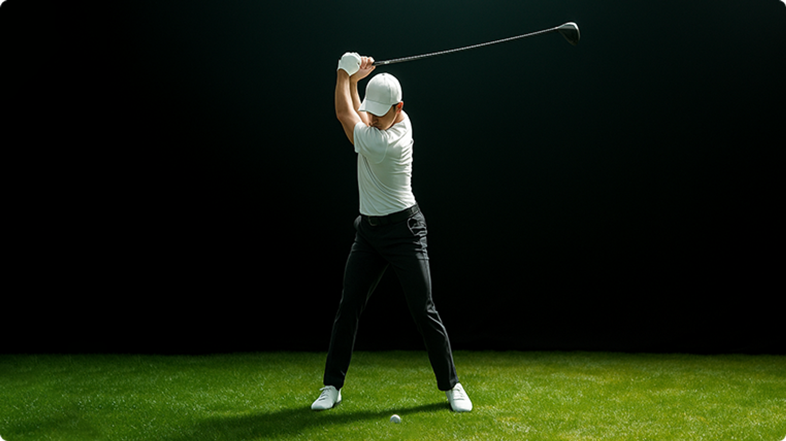 Golfer swinging a club on green grass against a dark background.
