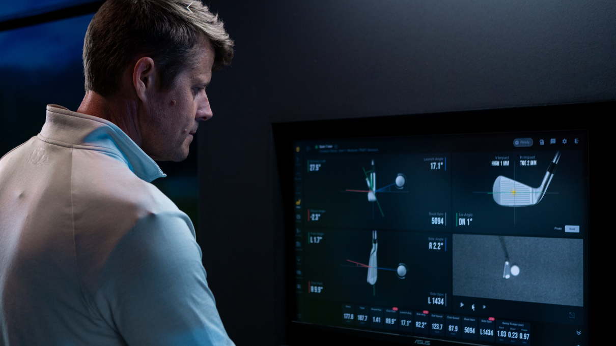 A man looks at a monitor displaying golf swing analysis and visualizations.