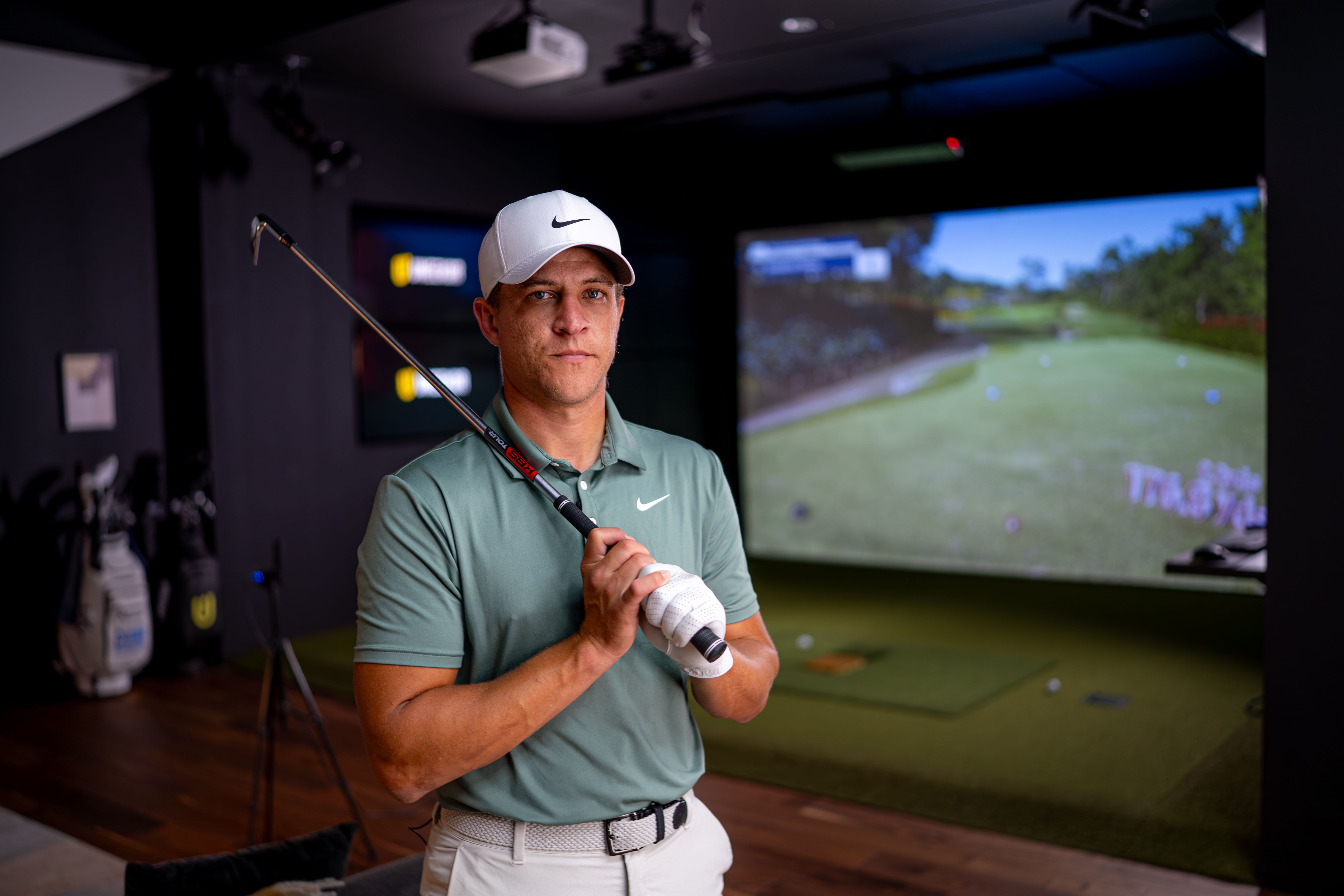 A man in a golf simulator holding a golf club.