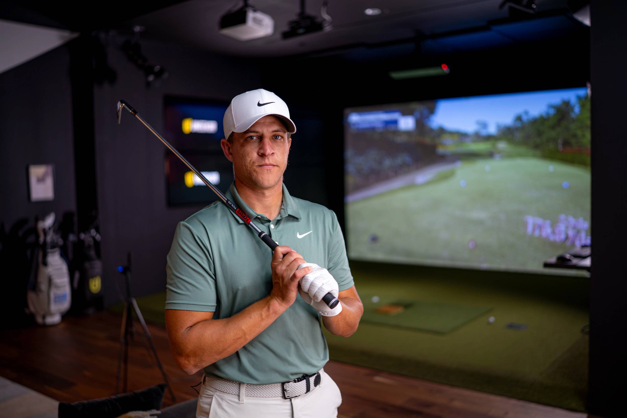A man in a golf simulator holding a golf club.