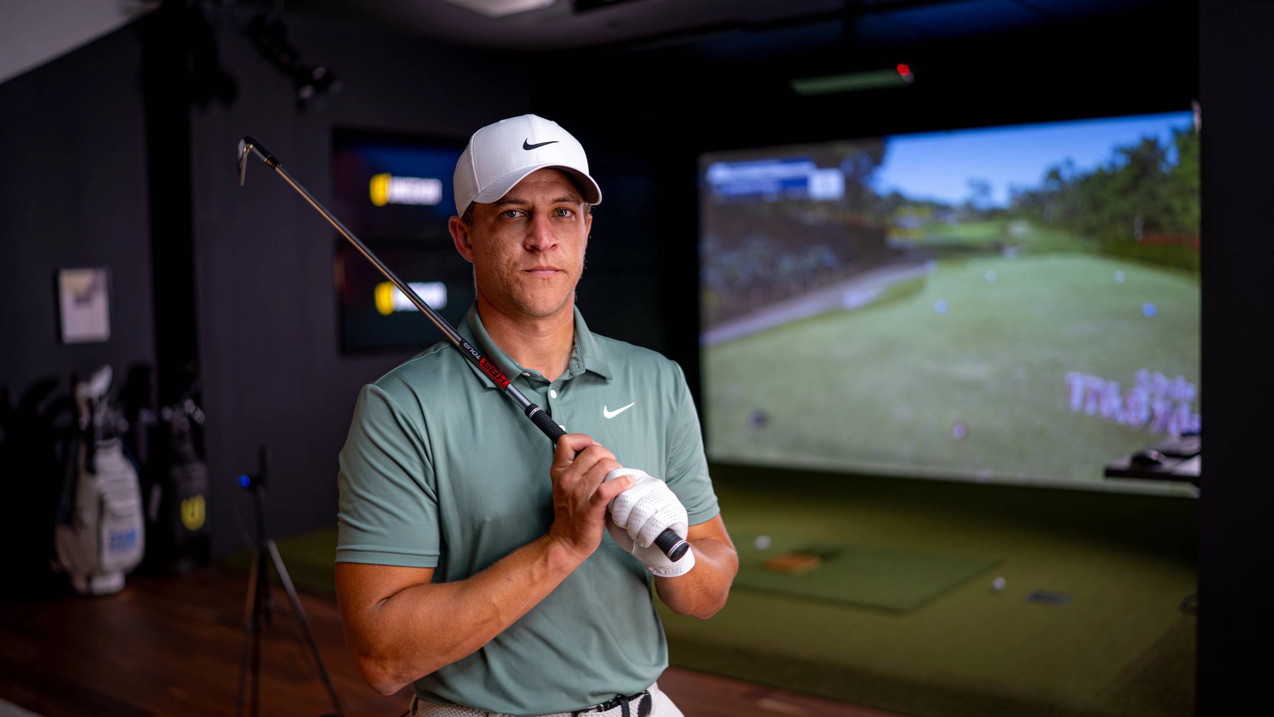 A man in a golf simulator holding a golf club.