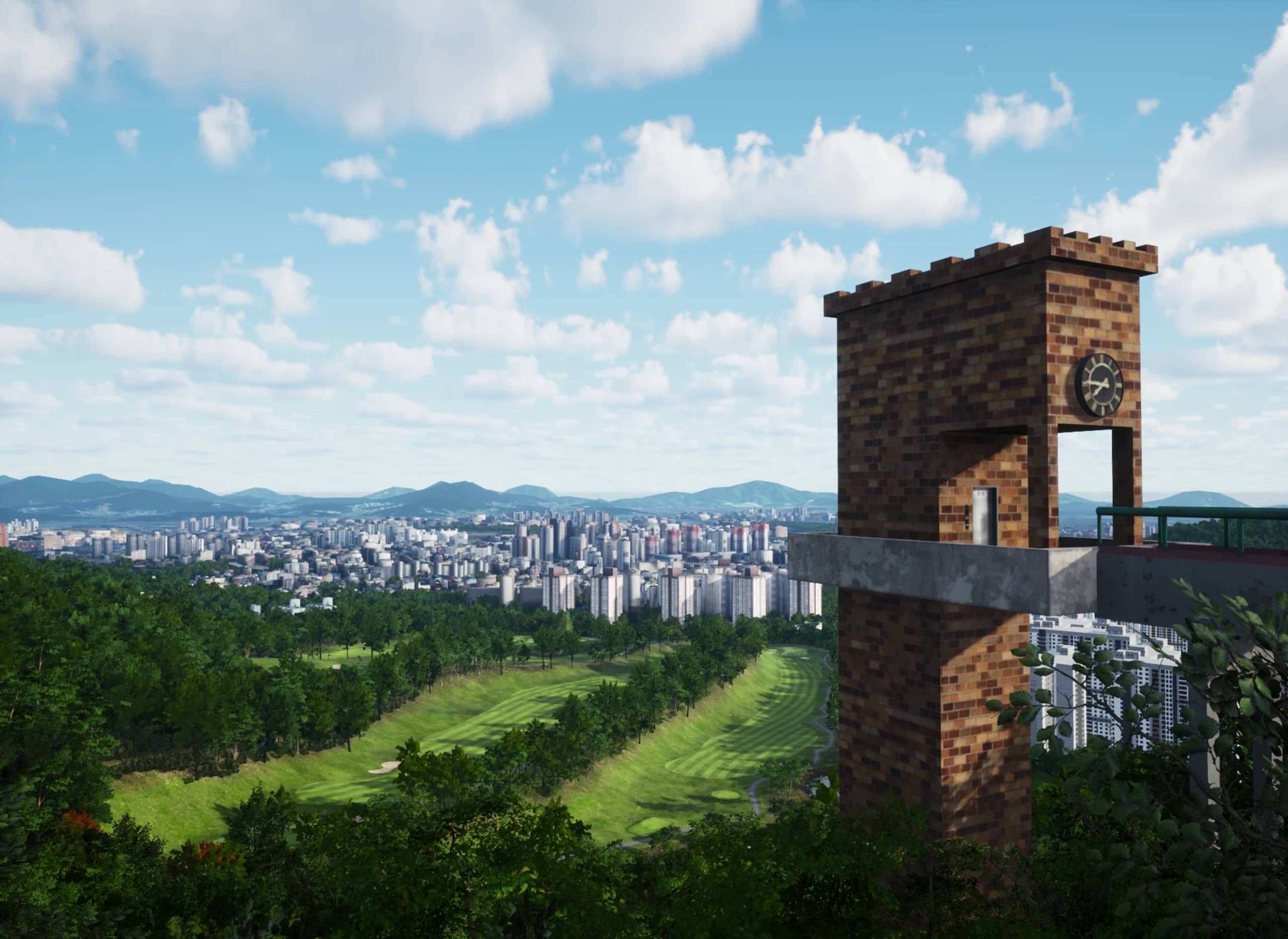 View from a brick clock tower overlooking a golf course, city, and distant mountains under a cloudy sky.