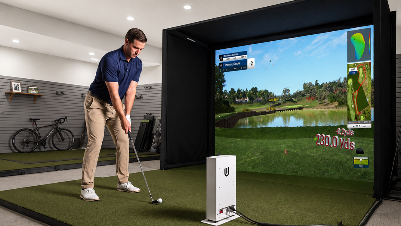 Man prepares to hit a golf ball on an indoor simulator with a virtual course projected on a large screen.