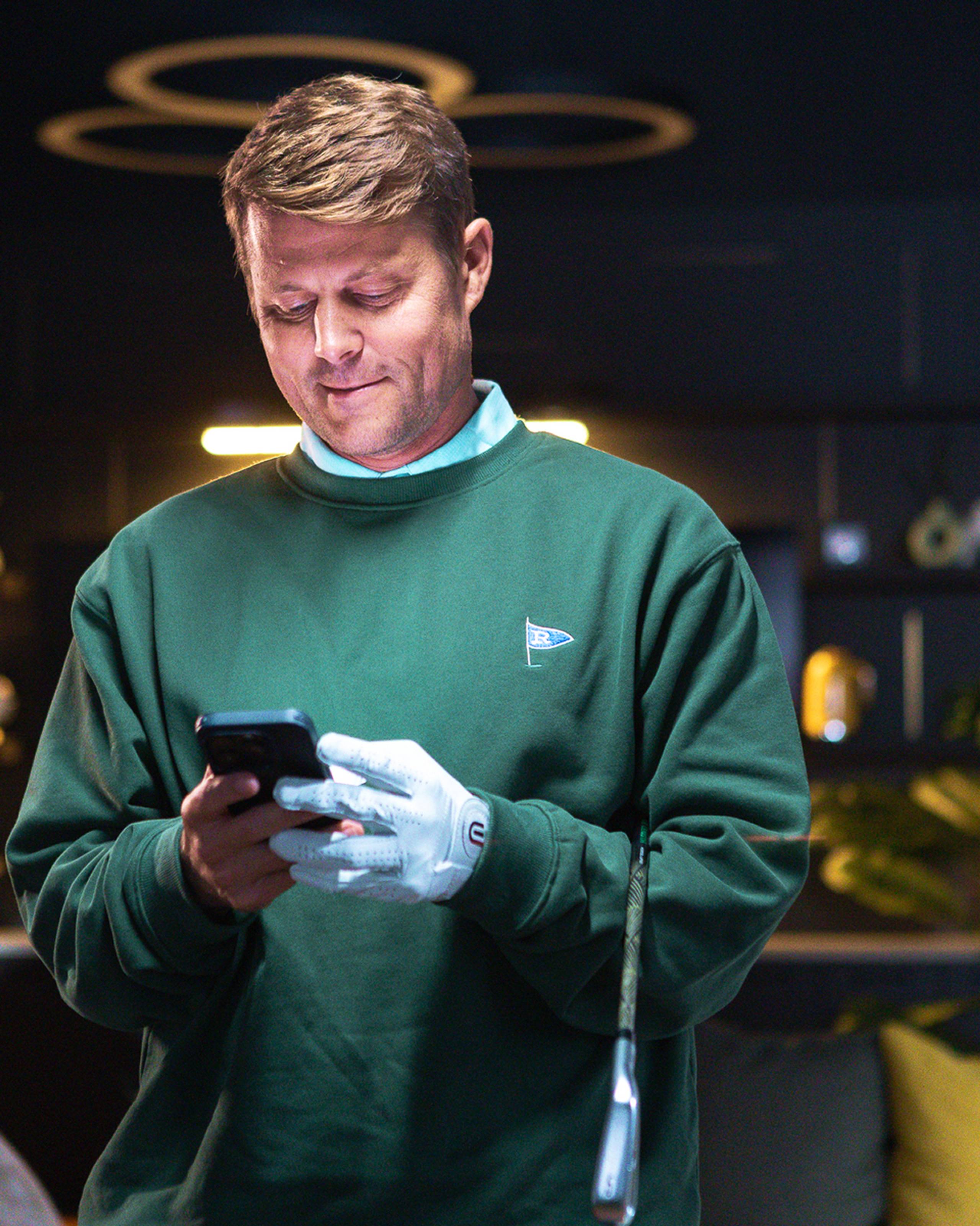 Man in golf attire checking his phone.
