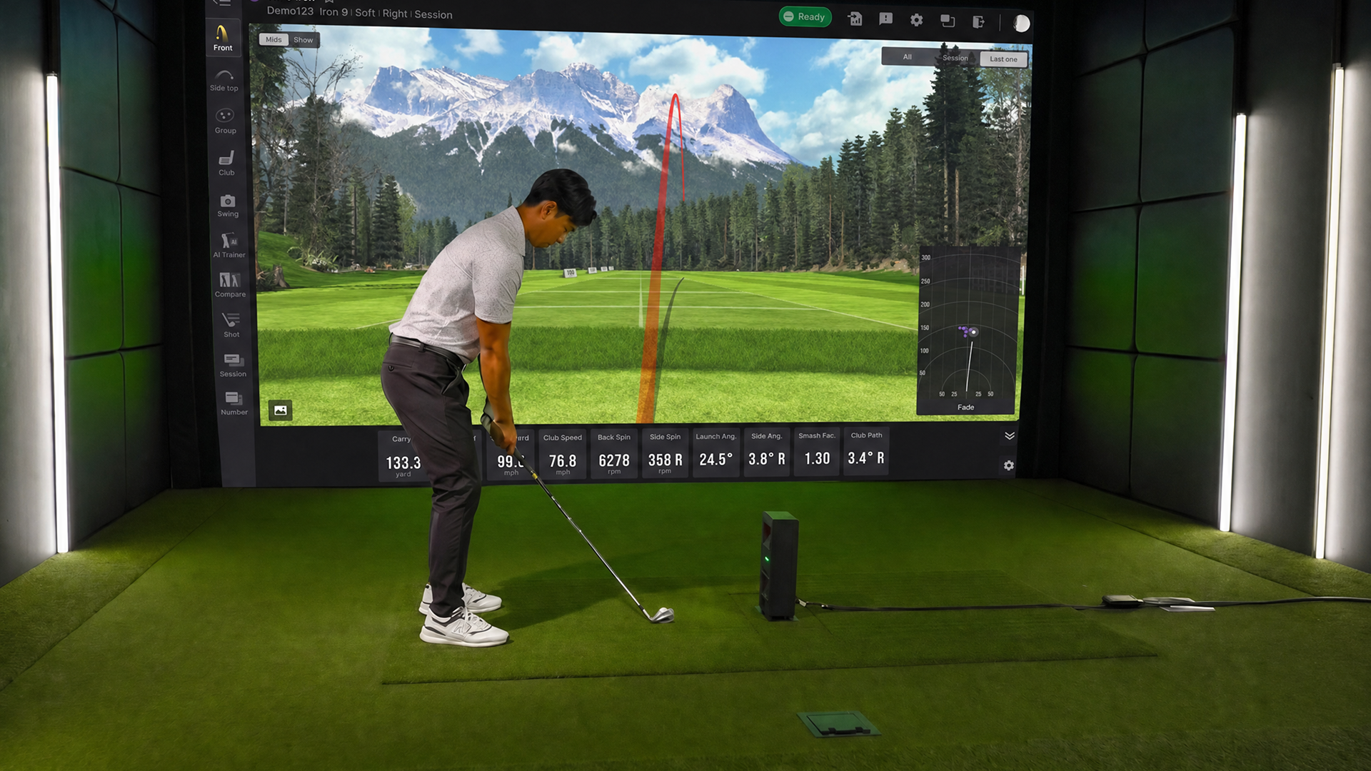 A man prepares to hit a golf ball in a golf simulator, with a launch monitor and a large screen displaying a virtual course.