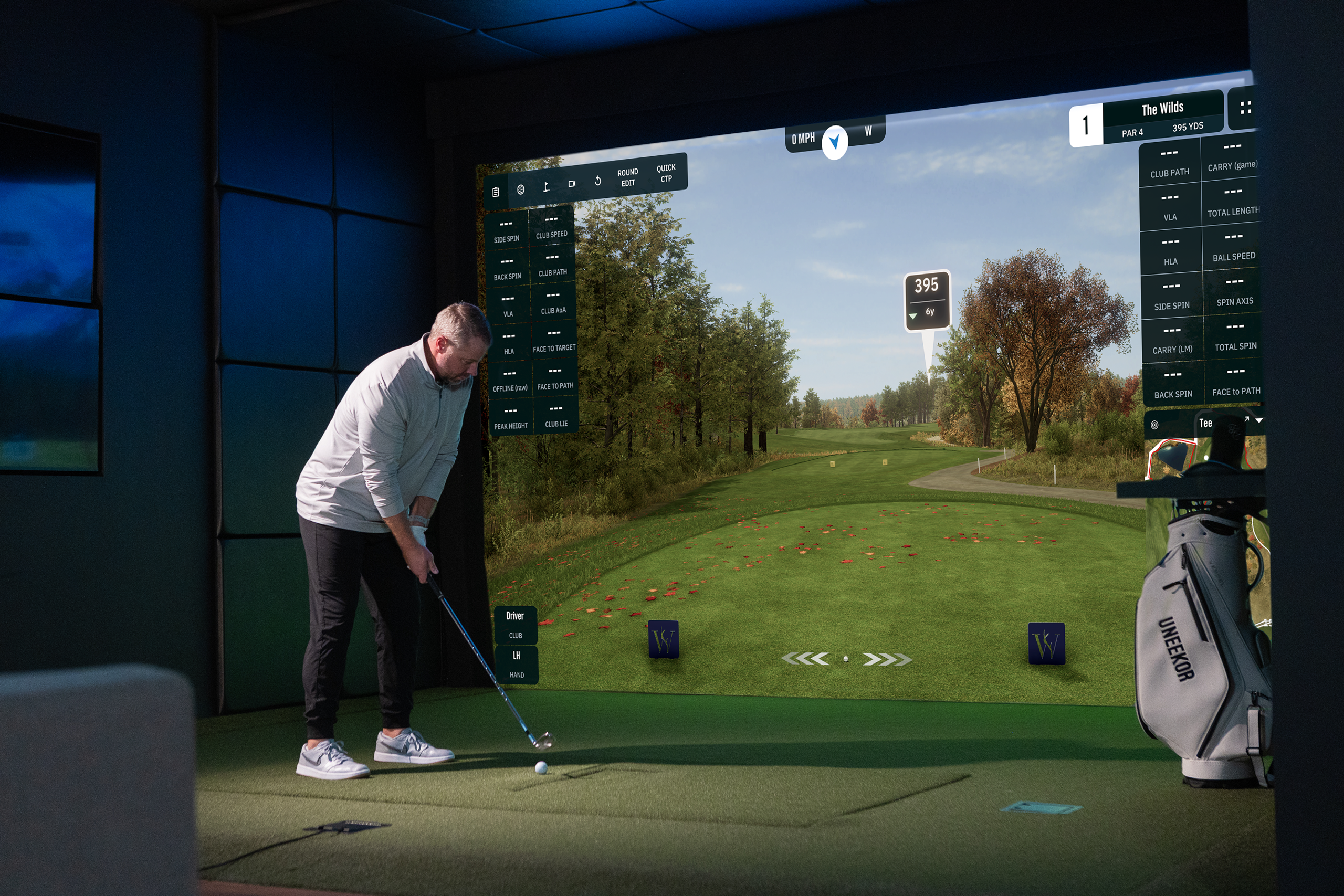 A man playing golf on an indoor simulator showing a virtual course.