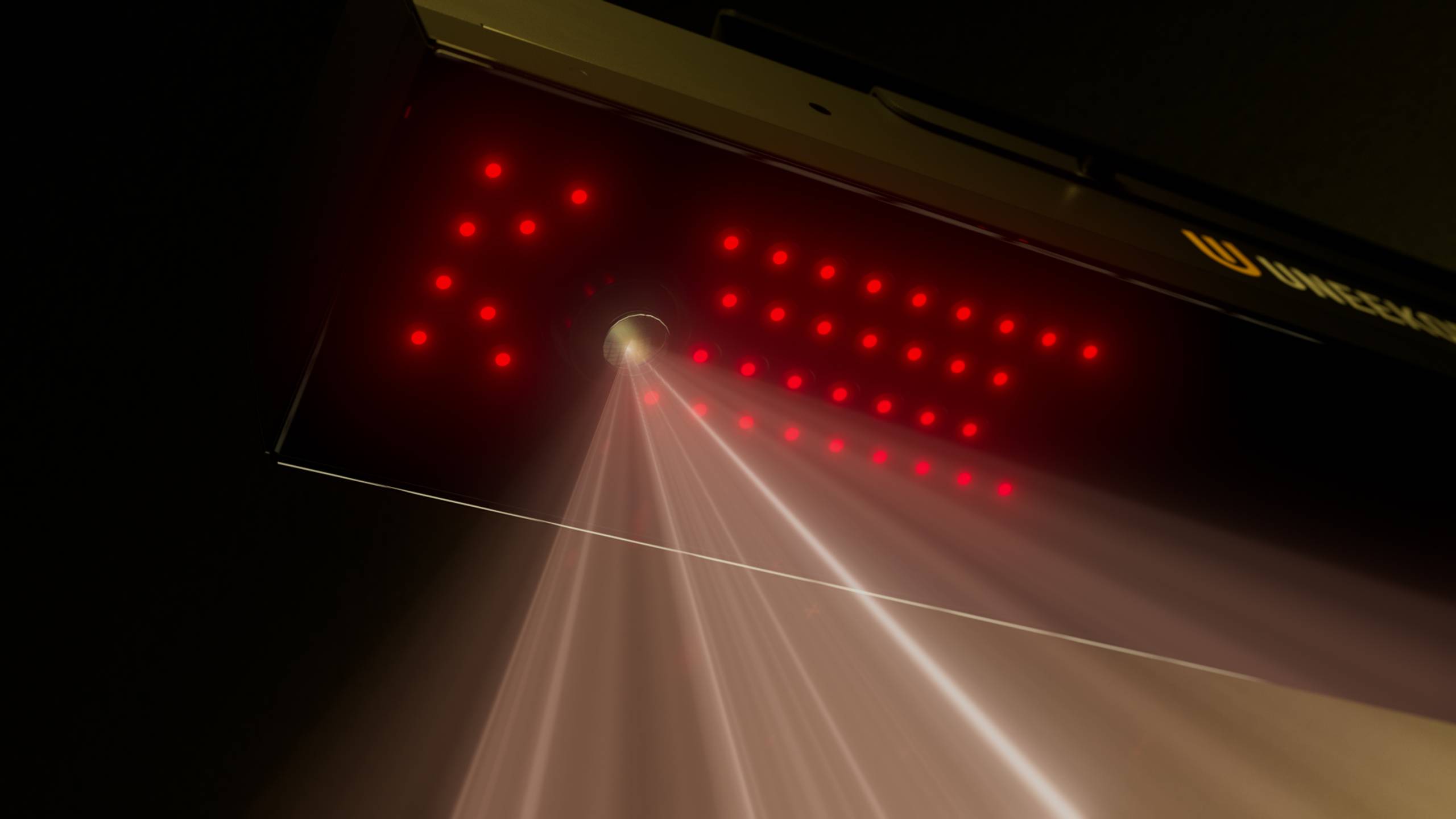 A scanner device with red LED lights forming an arrow shape emits multiple red light beams, with "UNIQUESCAN" visible on its surface.