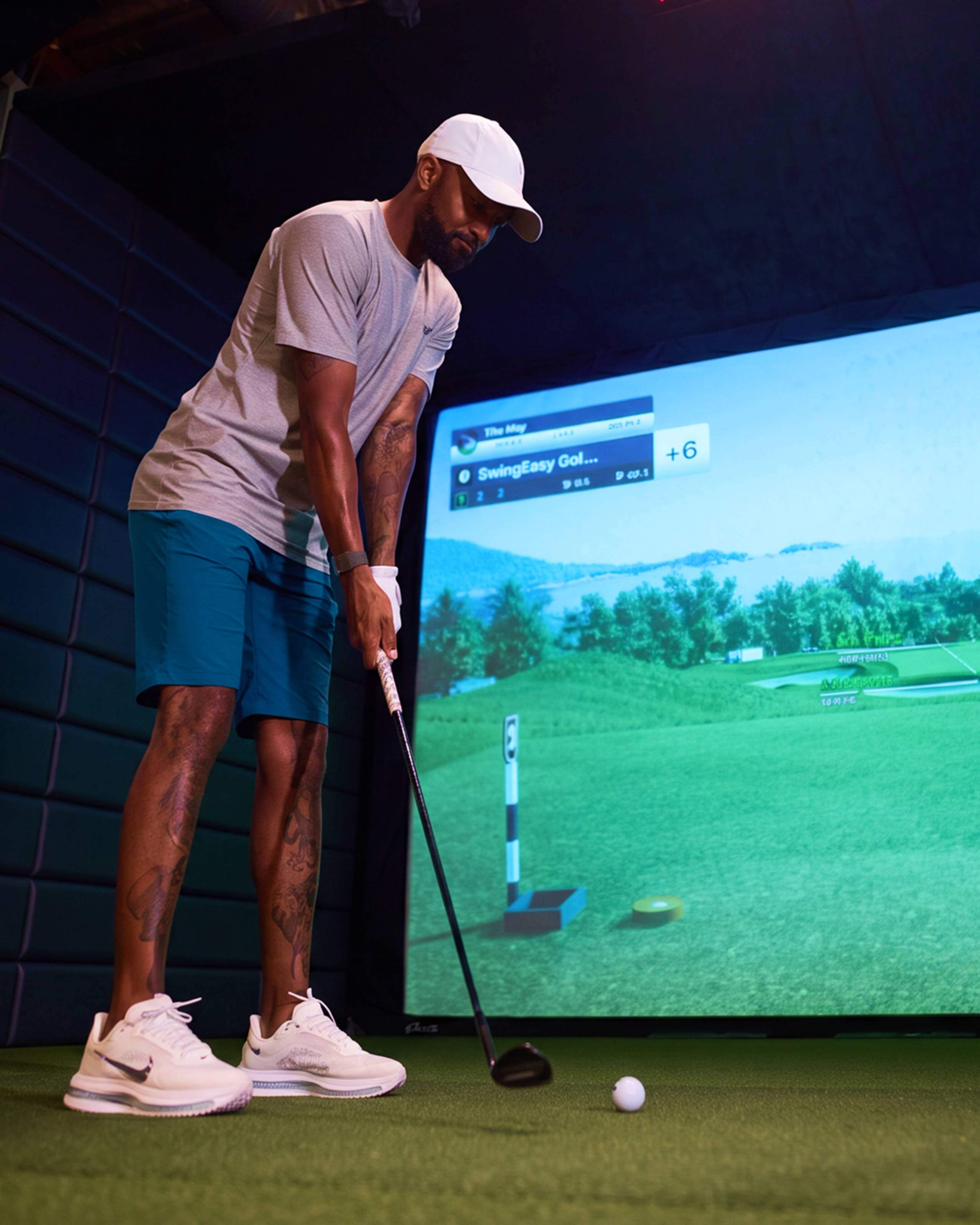 A man in athletic wear addresses a golf ball in a virtual golf simulator.
