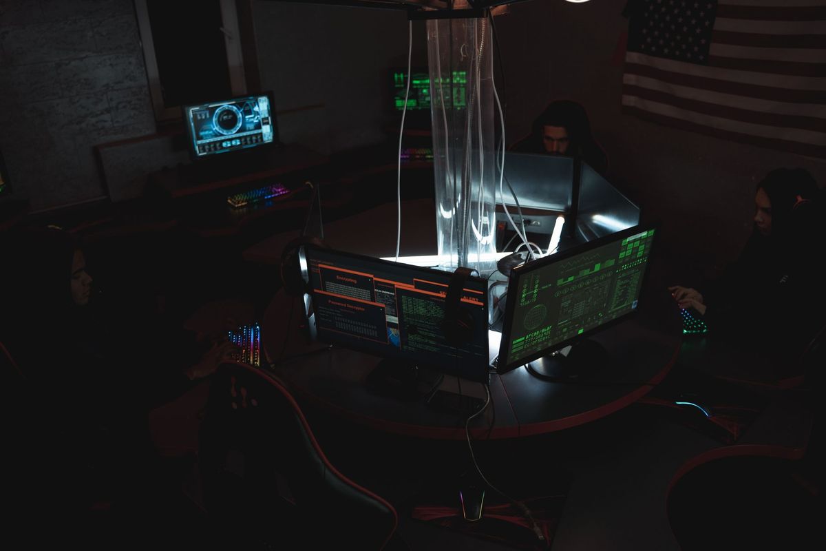 Team of cybersecurity experts collaboratively working on data protection in a dimly lit room filled with computers.